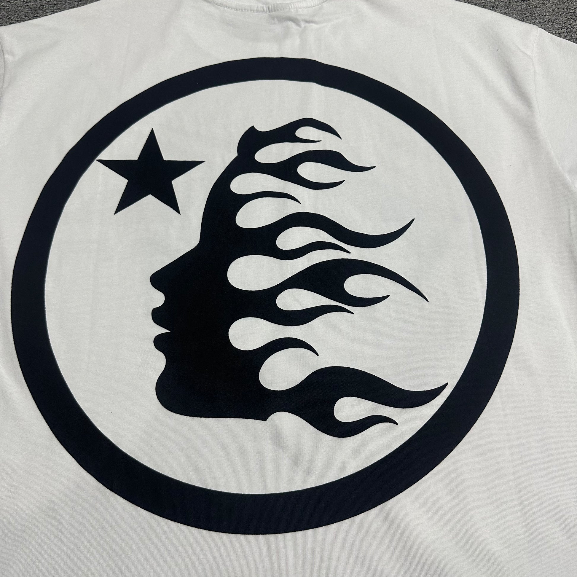 Full black Hellstar classic logo graphic on white rhinestone T-shirt
Full rhinestone decoration surrounding the Hellstar logo on white T-shirt
Detailed crystal placement around the Hellstar logo graphic
Black Hellstar classic logo graphic detail on white T-shirt