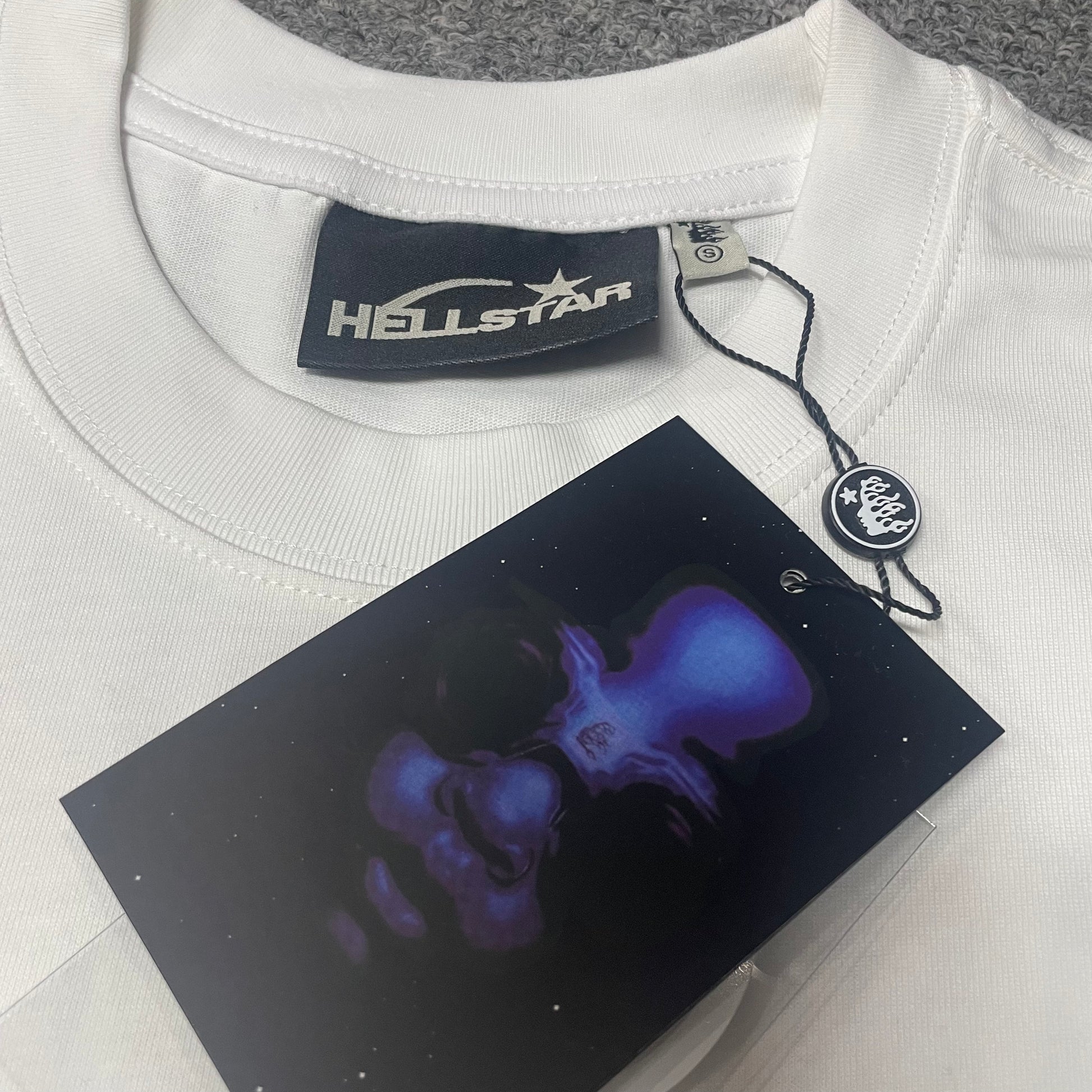 Crew neck collar and stitching detail on Hellstar H Blue Flame T-shirt
Hellstar woven neck label inside H Blue Flame white T-shirt
Hellstar size label detail inside H Blue Flame white T-shirt
Hellstar branded hangtag attached to H Blue Flame white T-shirt