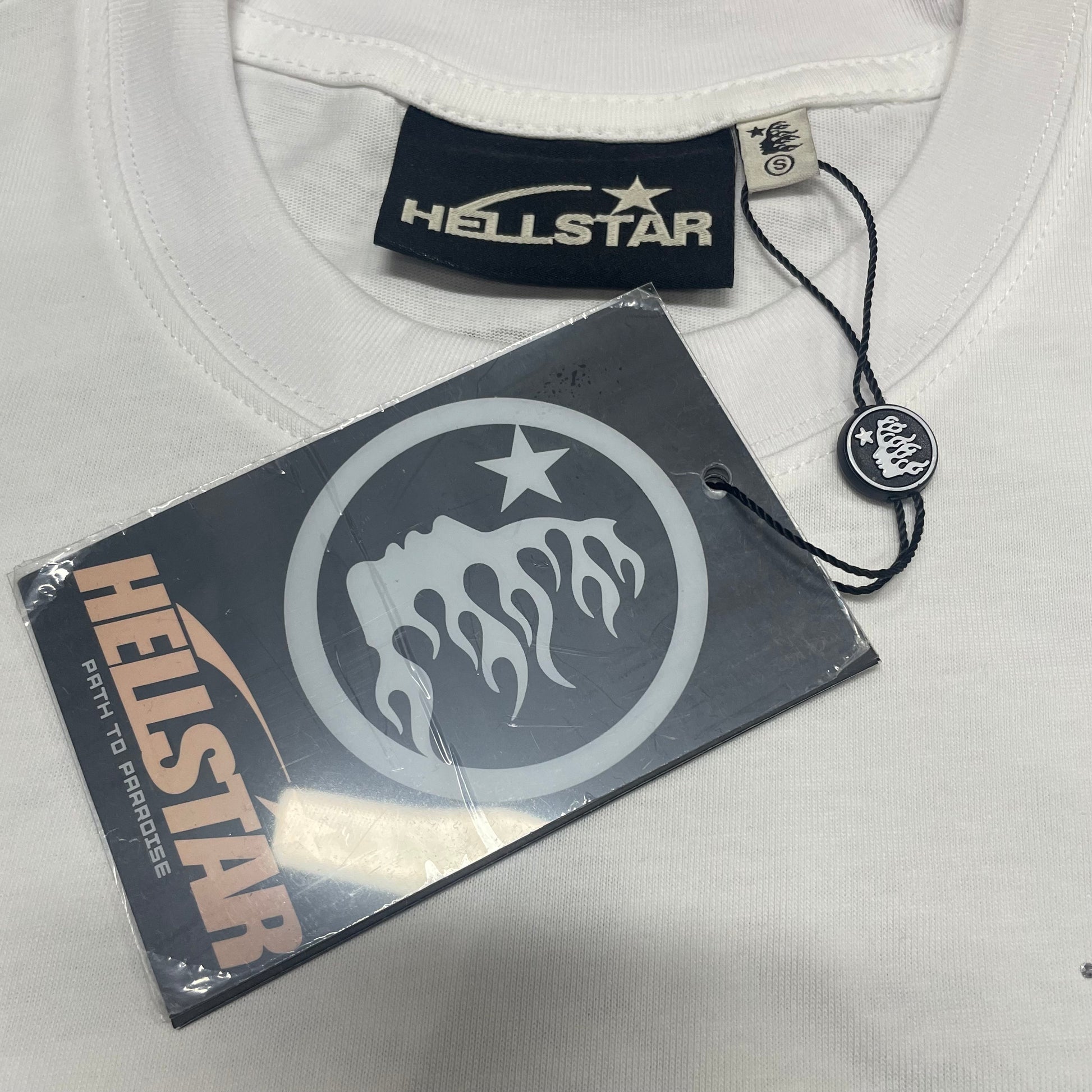 Crew neck collar and stitching detail on Hellstar Sports Core T-shirt
Hellstar woven neck label inside Sports Core Rhinestone white T-shirt
Hellstar size label detail inside Sports Core white T-shirt
Hellstar branded hangtag attached to Sports Core Rhinestone T-shirt