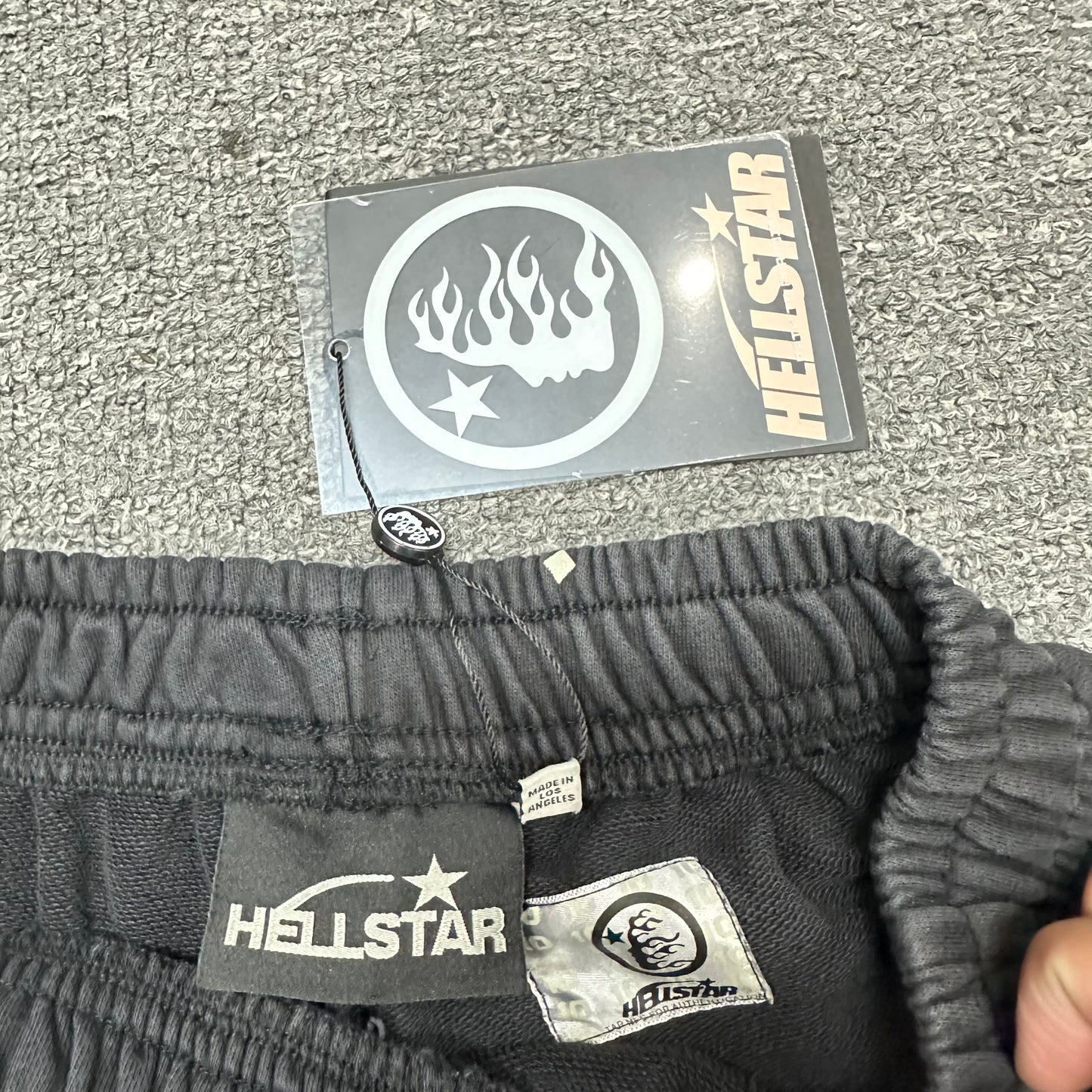 Cream drawstring detail on Hellstar washed black graphic shorts
Close-up of metal drawstring tips on Hellstar Path to Paradise shorts
Hellstar branded waistband label inside Path to Paradise shorts
Size label inside Hellstar Path to Paradise black shorts
Hellstar branded hang tag attached to Path to Paradise shorts
Fabric composition and care label inside Hellstar Path to Paradise shorts
NFC tag detail on Hellstar Path to Paradise graphic shorts