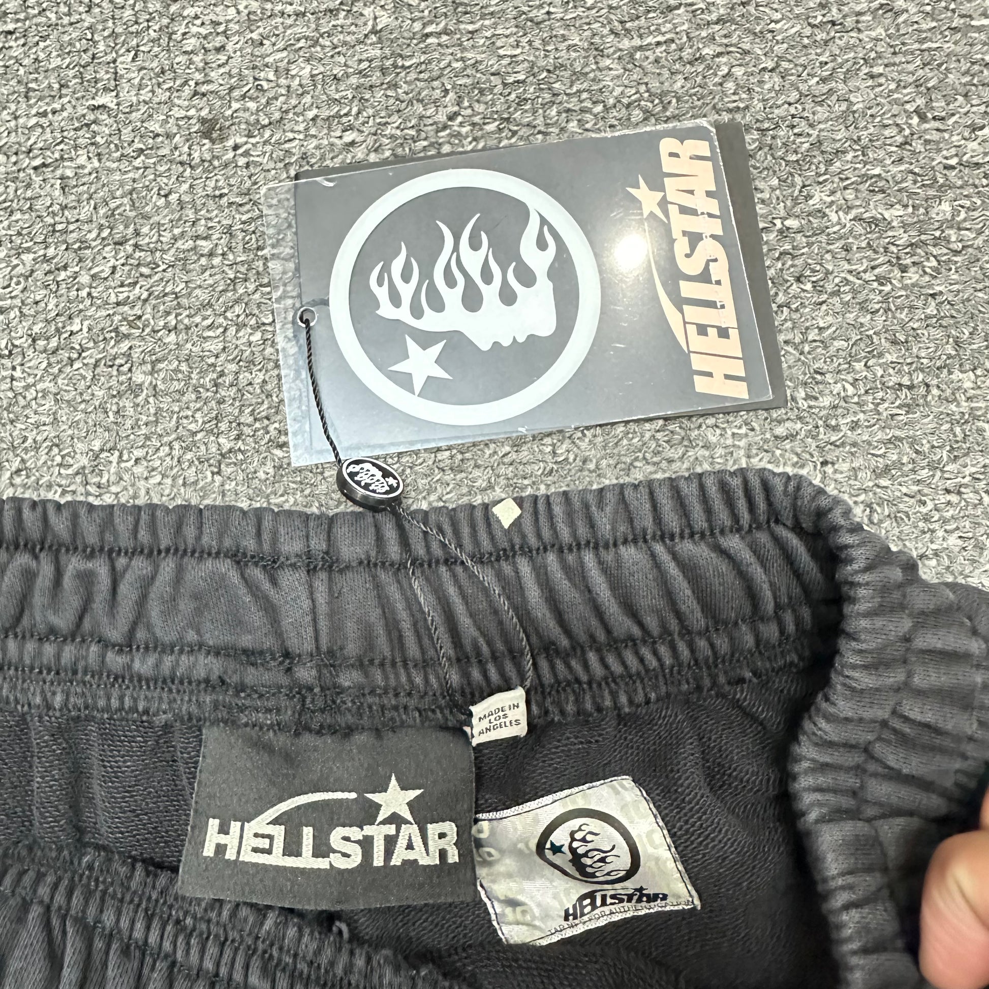 Cream drawstring detail on Hellstar washed black graphic shorts
Close-up of metal drawstring tips on Hellstar Path to Paradise shorts
Hellstar branded waistband label inside Path to Paradise shorts
Size label inside Hellstar Path to Paradise black shorts
Hellstar branded hang tag attached to Path to Paradise shorts
Fabric composition and care label inside Hellstar Path to Paradise shorts
NFC tag detail on Hellstar Path to Paradise graphic shorts