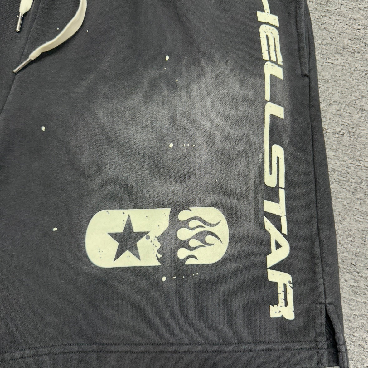 Vertical cream Hellstar logo printed on the left leg of black shorts
Vertical cream Hellstar logo printed on the right leg of black shorts
Signature Hellstar flame-face logo printed on the right leg of black shorts
Close-up of cream star detail beside the Hellstar flame-face logo