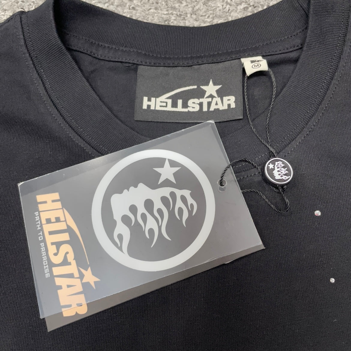 Hellstar neck label inside rhinestone distressed black T-shirt
Hellstar branded hang tag attached to washed black rhinestone T-shirt