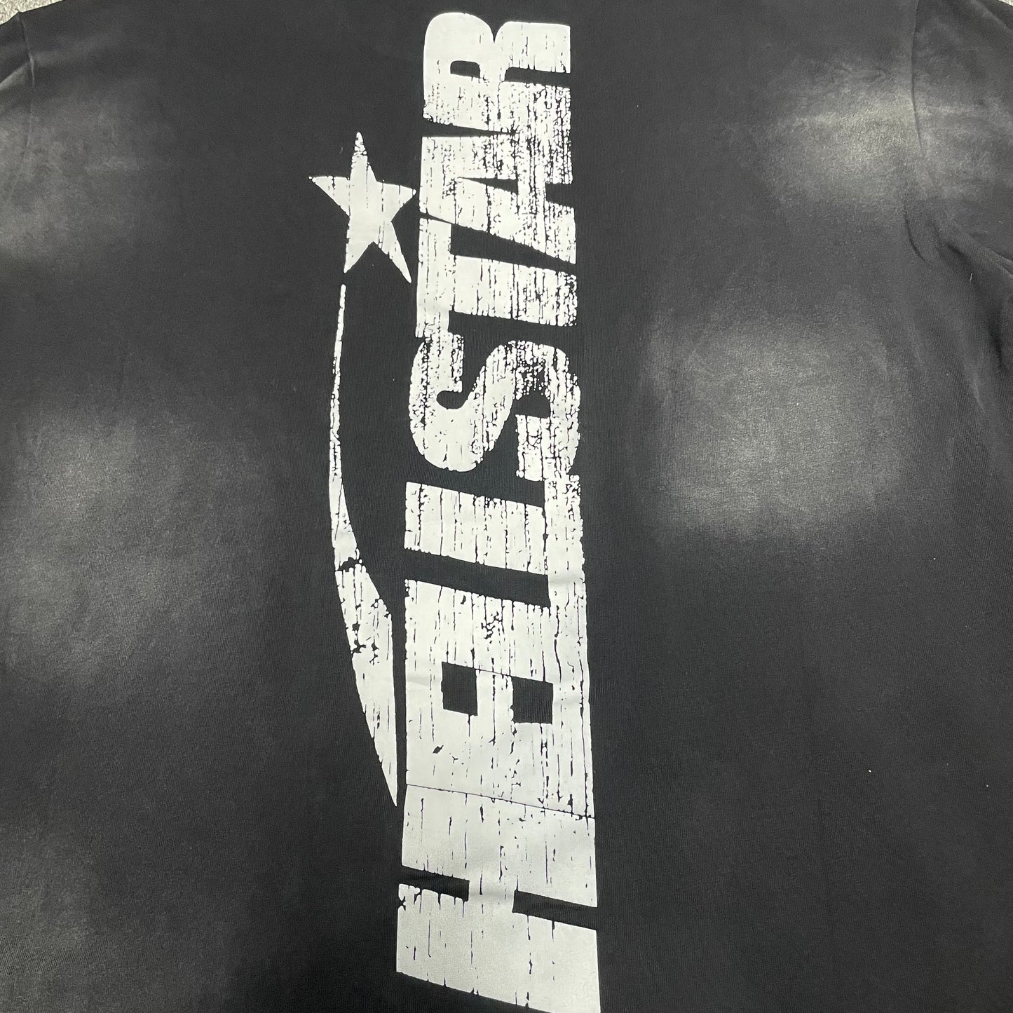 Full oversized Hellstar Flame Face and star graphic on washed black T-shirt
Close-up of white Hellstar Flame Face graphic on black T-shirt
Detailed view of distressed Hellstar Flame Face print texture
Close-up of white star graphic beside the Hellstar Flame Face design