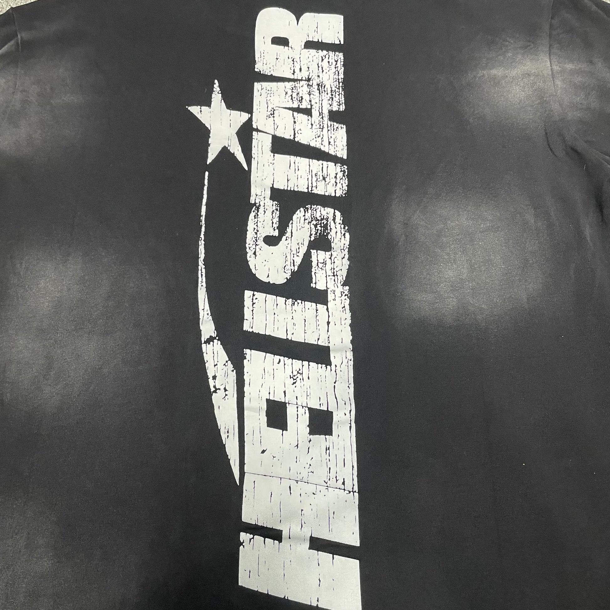 Full oversized Hellstar Flame Face and star graphic on washed black T-shirt
Close-up of white Hellstar Flame Face graphic on black T-shirt
Detailed view of distressed Hellstar Flame Face print texture
Close-up of white star graphic beside the Hellstar Flame Face design
