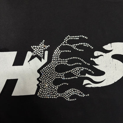 Wide Hellstar chest logo with rhinestone flame-face detail on black T-shirt
Double-sided Hellstar Studios graphics with rhinestone and distressed print details
Reflective rhinestone detailing inside the Hellstar front chest logo