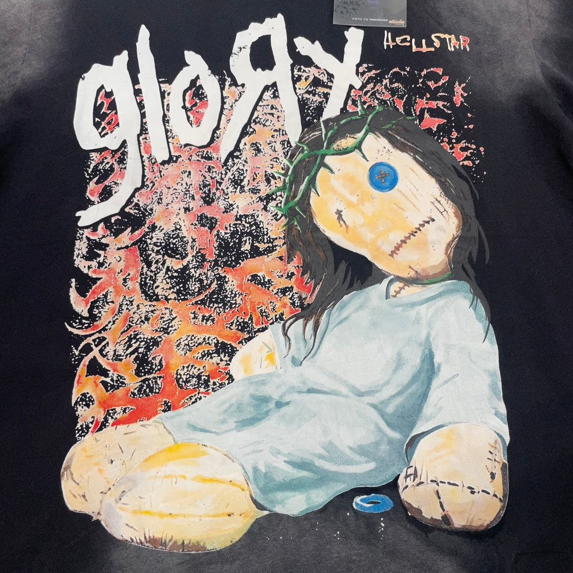 Oversized Hellstar Glory Doll graphic printed on washed black T-shirt
Full front Glory Doll artwork on Hellstar washed black graphic T-shirt
Close-up of button eye and stitched face details on Hellstar Glory Doll graphic
Close-up of jumbo screen print on Hellstar Glory Doll T-shirt
Detailed view of distressed colors and textured Glory Doll graphic print