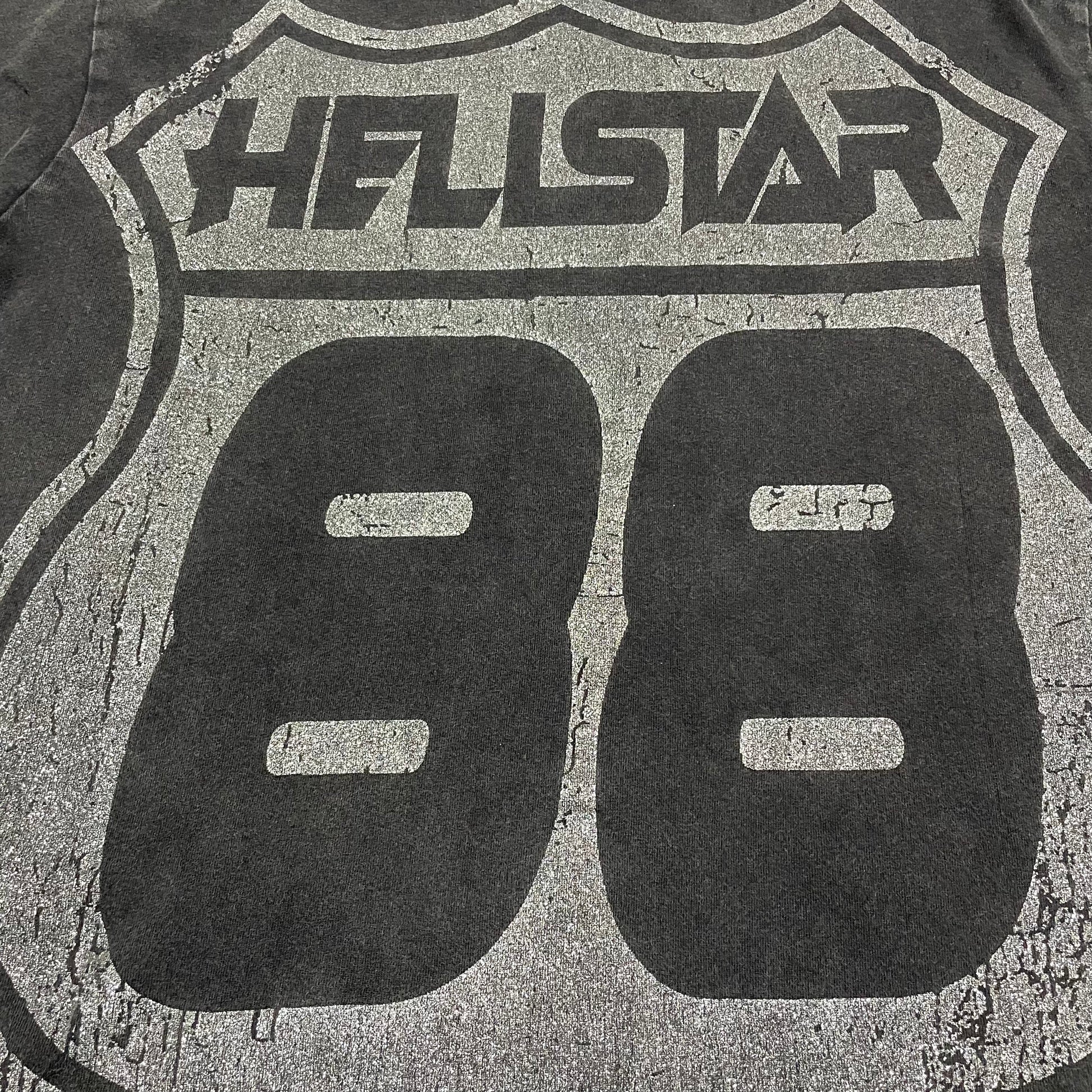 Oversized Hellstar Sports logo and mouth graphic on washed black T-shirt
Distressed Hellstar Sports lettering above a large face and mouth graphic
Close-up of white Hellstar Sports logo print on washed black T-shirt
Close-up of oversized face artwork on Hellstar Sports graphic T-shirt
Close-up of large mouth and tongue graphic on Hellstar Sports T-shirt
Detailed view of teeth lips and tongue artwork on Hellstar Sports T-shirt
Close-up of hand and finger details surrounding the mouth graphic
