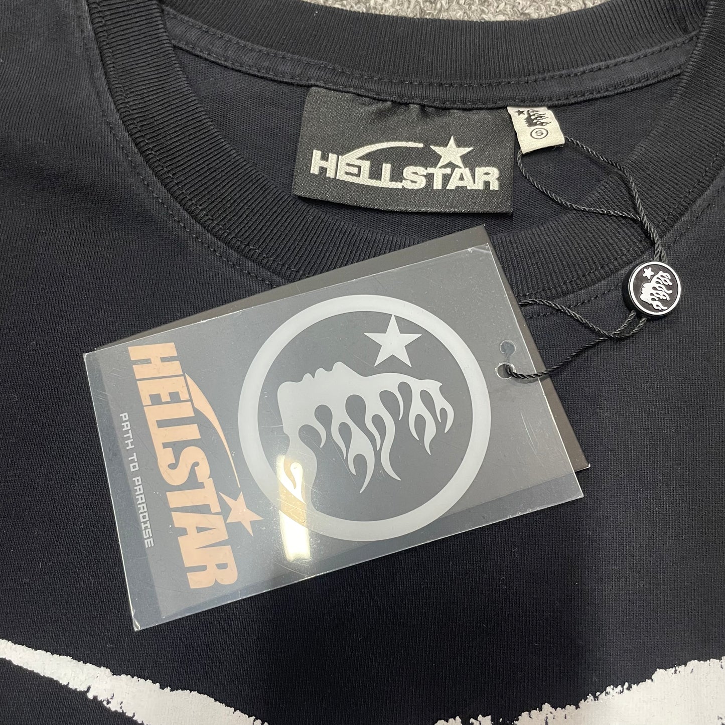 Close-up of ribbed crew neck and neckline stitching on Hellstar T-shirt
Hellstar branded neck label inside Spiderweb Sport Logo T-shirt
Size label inside Hellstar Spiderweb Sport Logo black T-shirt
Hellstar branded hang tag attached to Spiderweb Sport Logo T-shirt