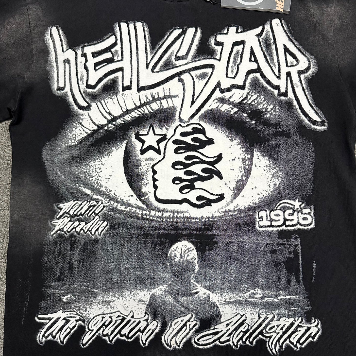 Full front Hellstar Eyeball Brainwashed graphic on washed black T-shirt
Monochrome Hellstar artwork featuring an oversized eye flame-face icon and futuristic text
Close-up of oversized eyeball graphic on Hellstar washed black T-shirt
Close-up of Hellstar flame-face icon inside the eyeball graphic