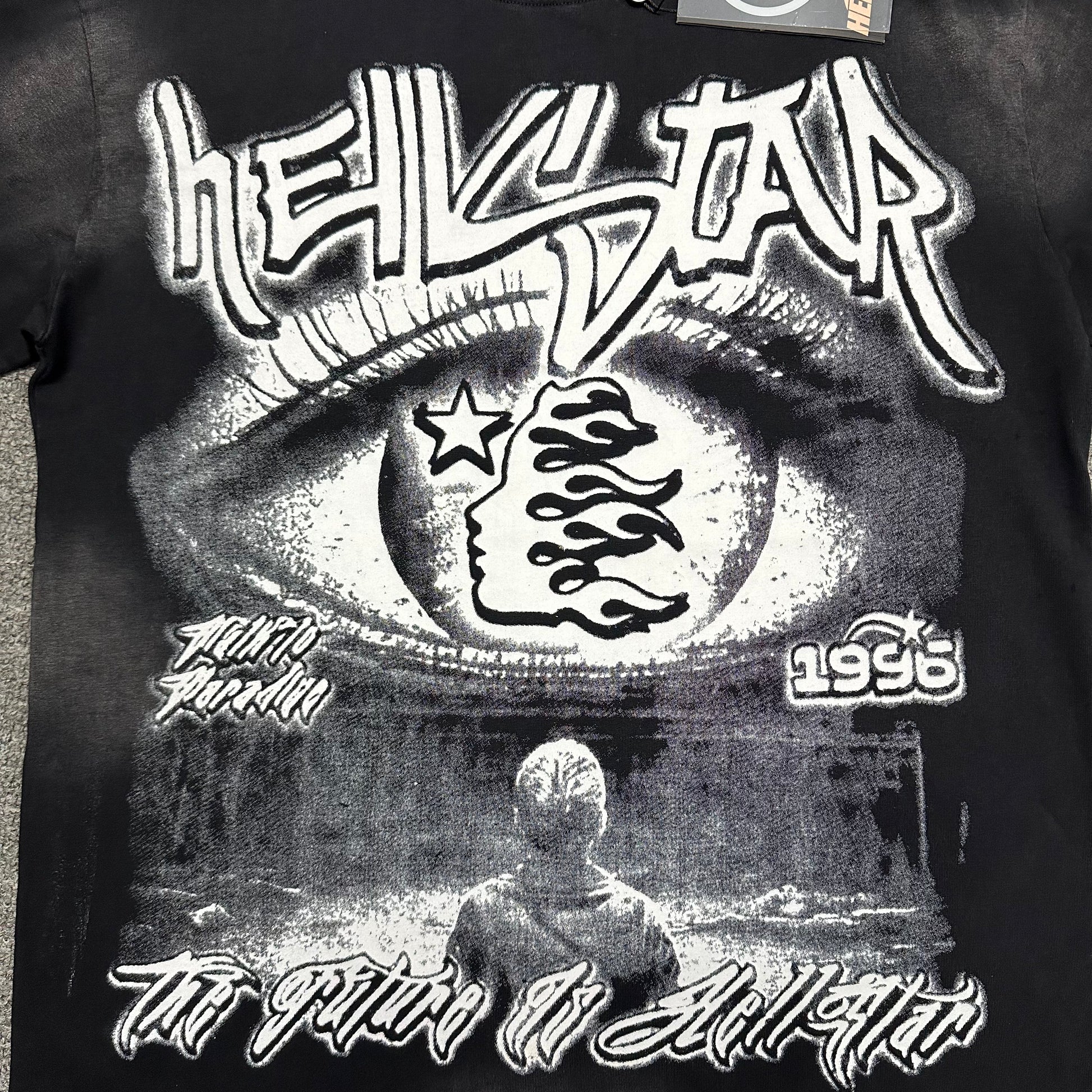 Full front Hellstar Eyeball Brainwashed graphic on washed black T-shirt
Monochrome Hellstar artwork featuring an oversized eye flame-face icon and futuristic text
Close-up of oversized eyeball graphic on Hellstar washed black T-shirt
Close-up of Hellstar flame-face icon inside the eyeball graphic