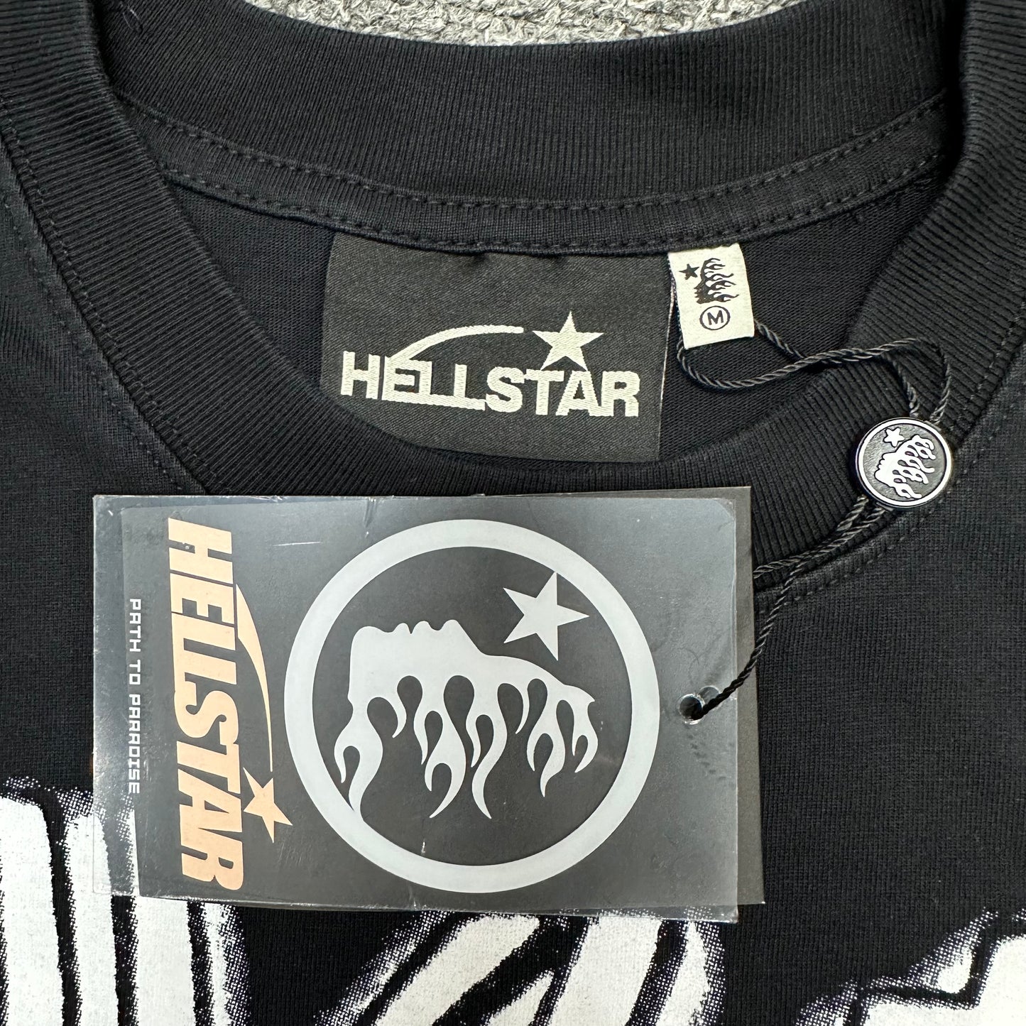 Close-up of ribbed crew neck and neckline stitching on Hellstar Eyeball T-shirt
Hellstar branded neck label inside Eyeball graphic black T-shirt
Size label inside Hellstar Eyeball washed black T-shirt
Hellstar branded hang tag attached to Eyeball graphic T-shirt