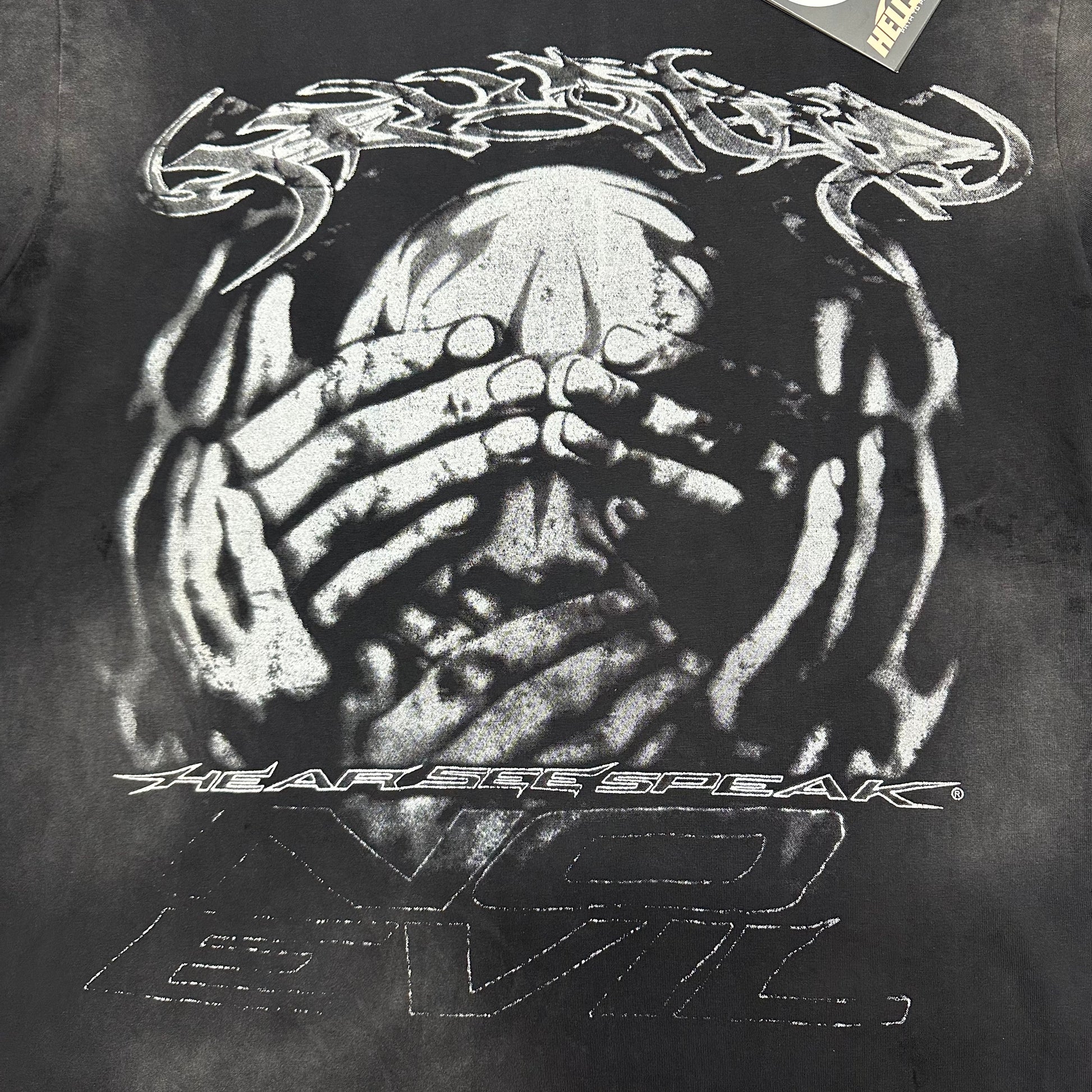 Oversized front No Evil face and hands graphic on Hellstar black T-shirt
Distressed monochrome artwork showing a face covered by layered hands
Close-up of Hellstar No Evil front graphic on washed black T-shirt
Close-up of monochrome face artwork on Hellstar No Evil T-shirt
Close-up of hands covering the eyes in Hellstar No Evil graphic
Detailed view of hands covering the ears in Hellstar No Evil artwork