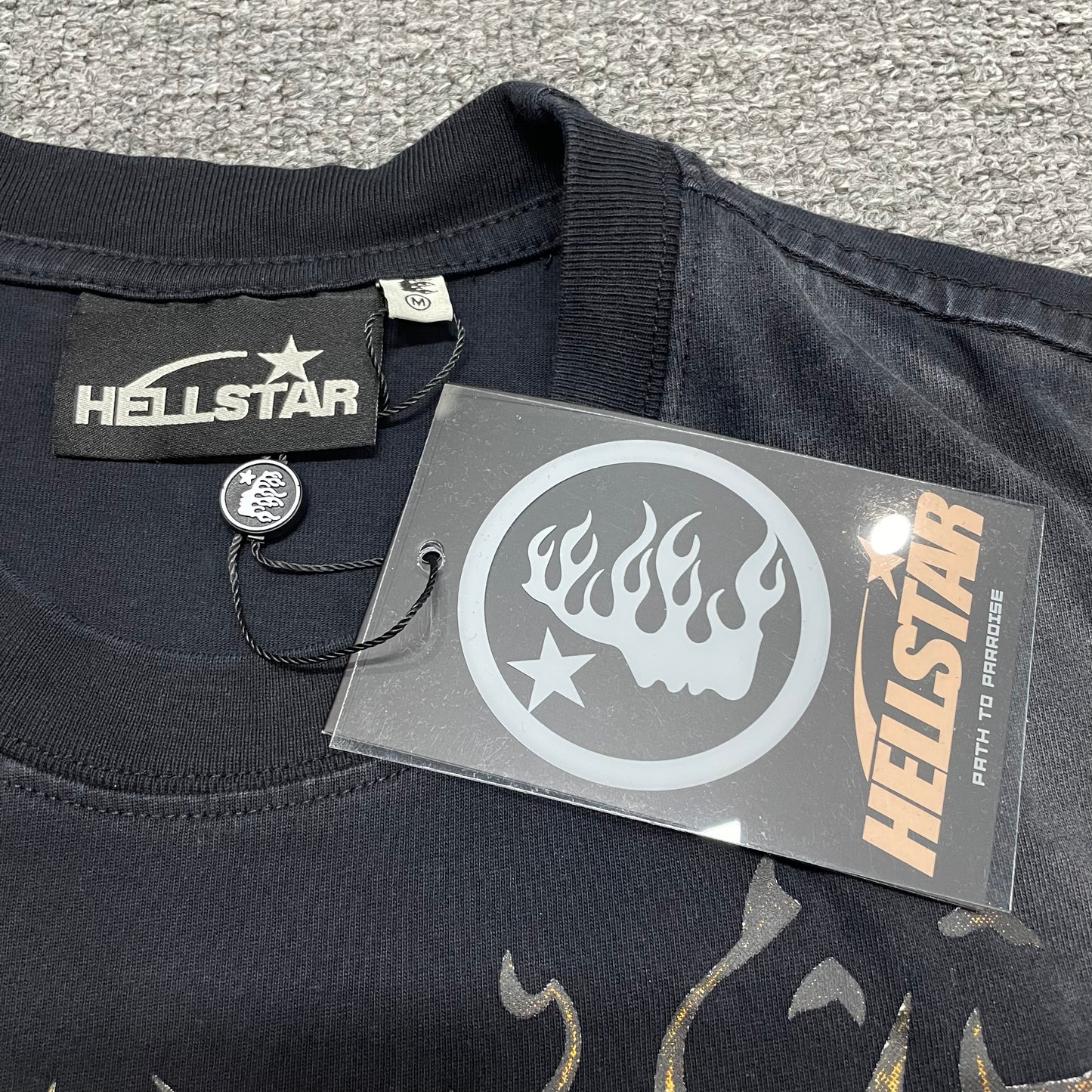 Close-up of ribbed crew neck and neckline stitching on Hellstar sleeveless T-shirt
Hellstar branded neck label inside Inner Peace Skeleton sleeveless T-shirt
Size label inside Hellstar Inner Peace Skeleton black sleeveless T-shirt
Hellstar branded hang tag attached to Inner Peace Skeleton sleeveless T-shirt