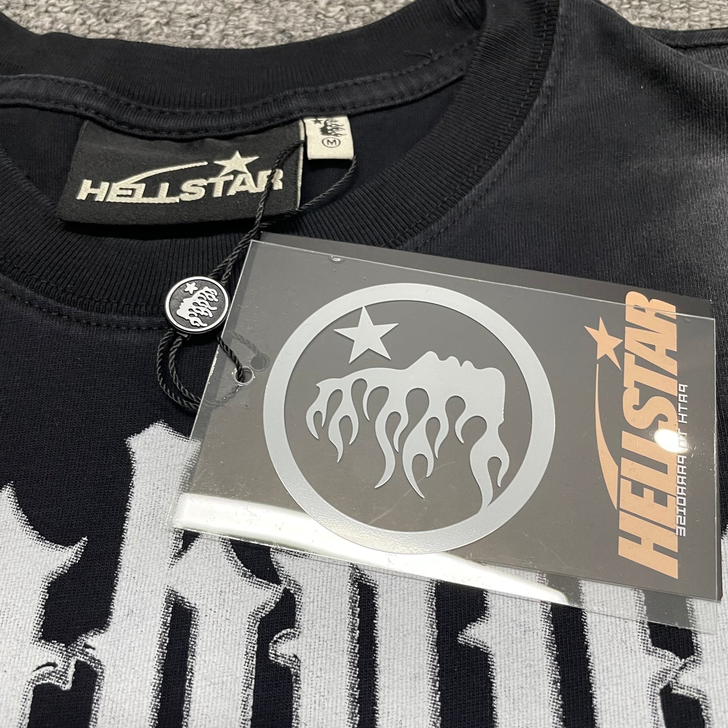 Hellstar branded neck label inside As Above So Below cutoff T-shirt
Size label inside Hellstar As Above So Below black T-shirt
Hellstar branded hang tag attached to As Above So Below cutoff T-shirt