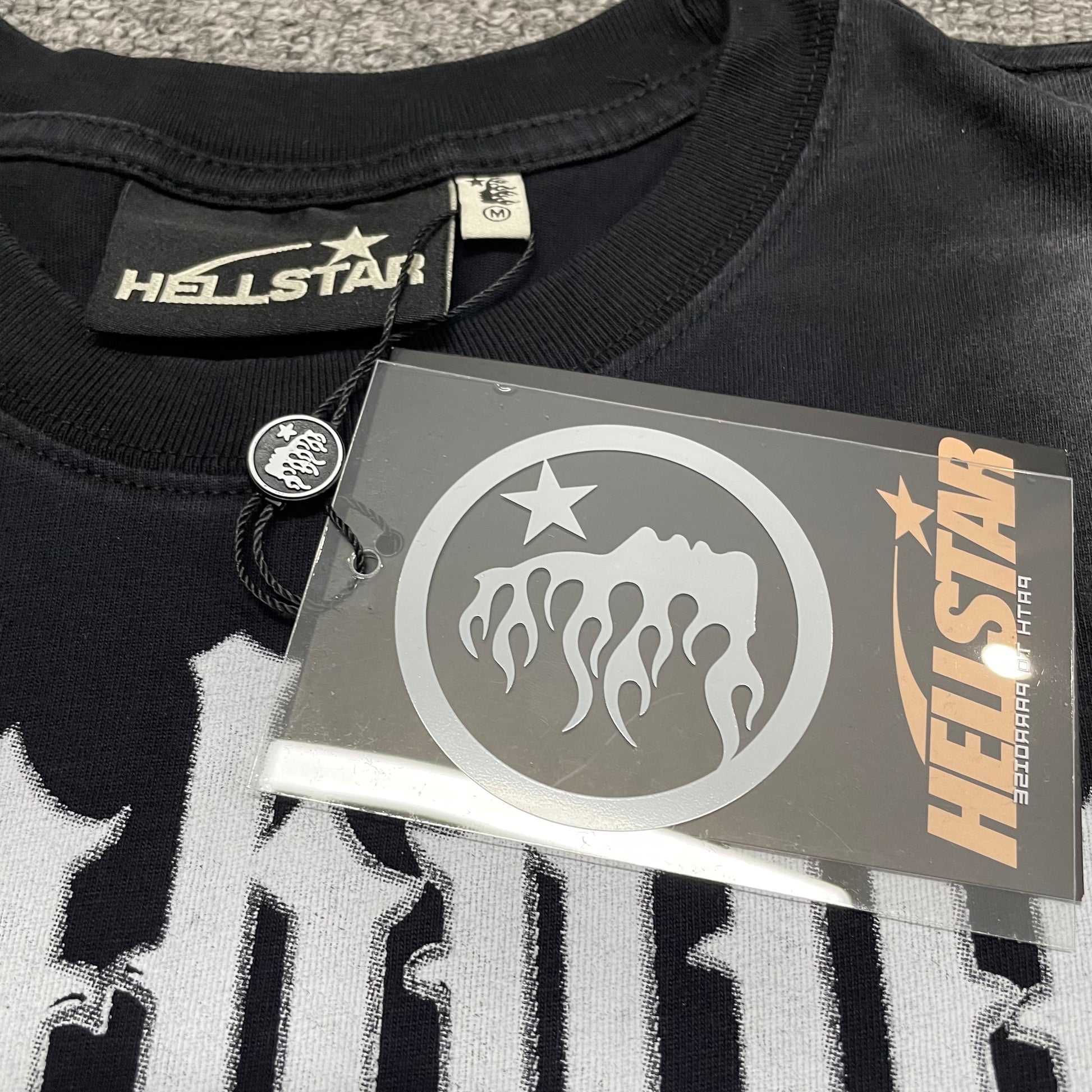 Hellstar branded neck label inside As Above So Below cutoff T-shirt
Size label inside Hellstar As Above So Below black T-shirt
Hellstar branded hang tag attached to As Above So Below cutoff T-shirt