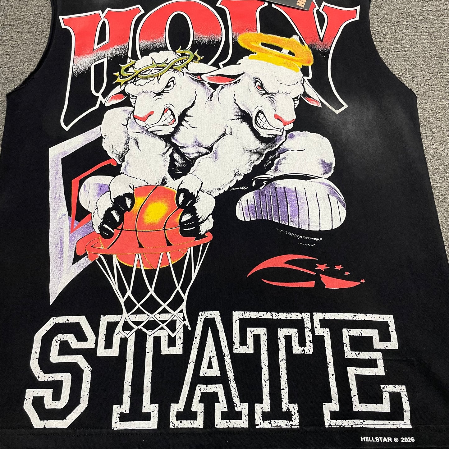 Hellstar Holy State two lambs basketball artwork with halo crown and varsity lettering
Hellstar 2 Lambs Holy State jumbo screen print texture and color detail
Hellstar Holy State halo and thorn crown lamb character print close-up
Hellstar Holy State distressed varsity lettering print close-up
Hellstar 2 Lambs basketball and hoop graphic print detail
Hellstar sleeveless T-shirt vintage black washed and faded fabric detail
