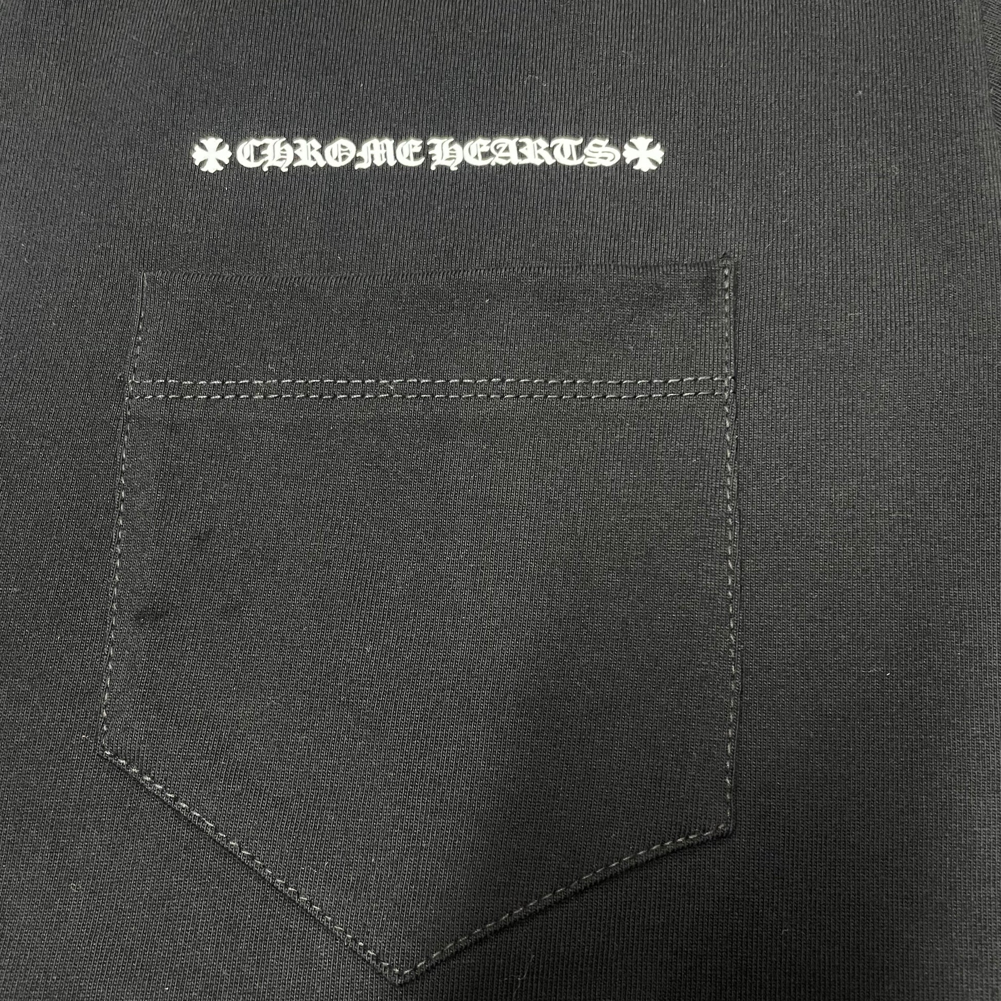 Chrome Hearts white logo print above the chest pocket on black T-shirt
Close-up of white Chrome Hearts lettering and front chest pocket print detail
