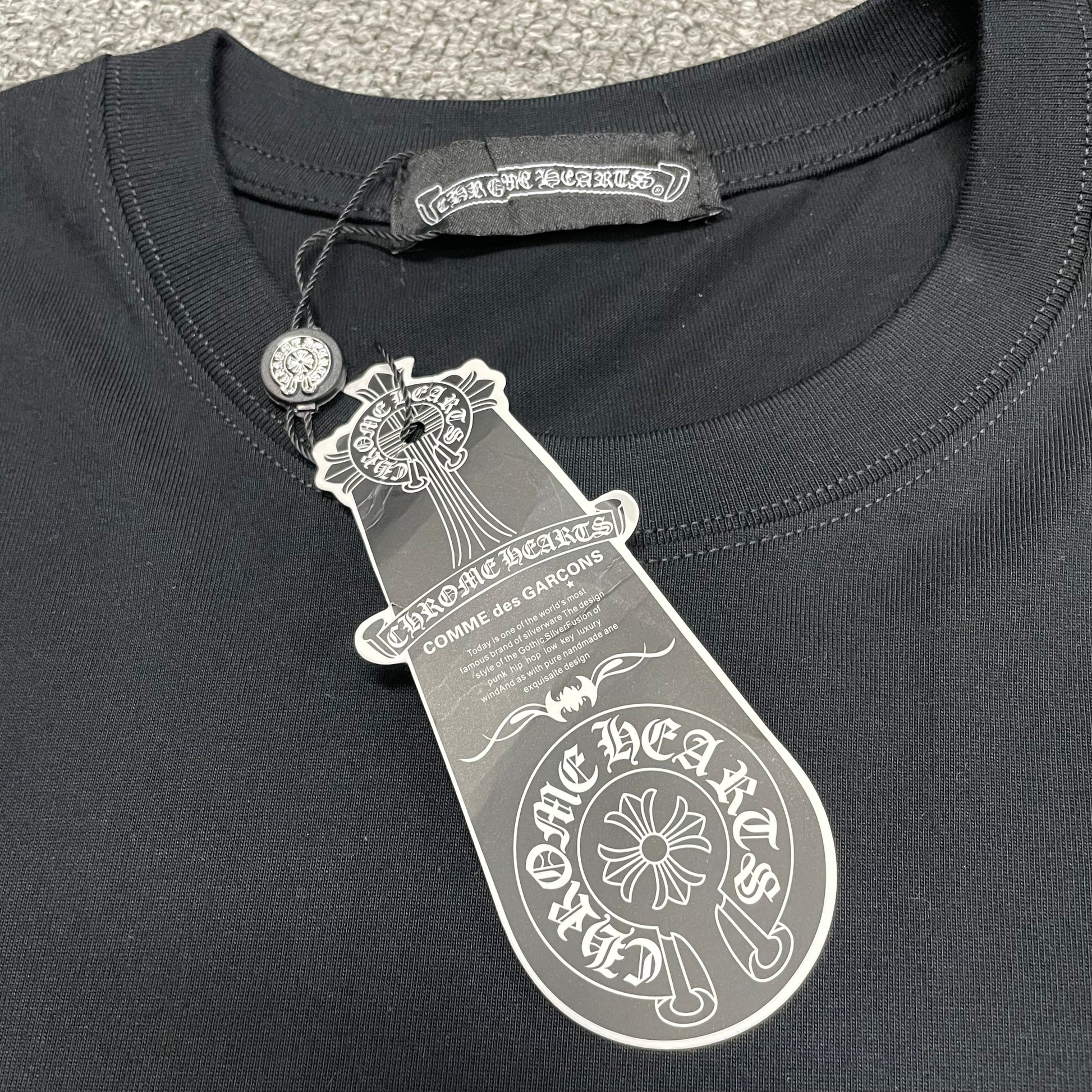 Chrome Hearts Floral Horseshoe T-shirt crew neck stitching hang tag and neck label details
Close-up of the crew neck stitching on Chrome Hearts Floral Horseshoe short sleeve T-shirt
Chrome Hearts Floral Horseshoe T-shirt hang tag and branded neck label close-up