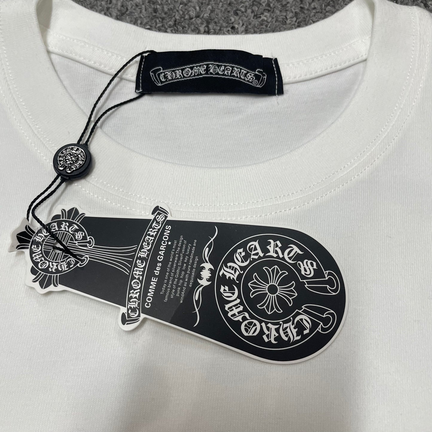 Chrome Hearts Floral Horseshoe T-shirt crew neck stitching hang tag and neck label details
Close-up of the crew neck stitching on Chrome Hearts Floral Horseshoe short sleeve T-shirt
Chrome Hearts Floral Horseshoe T-shirt hang tag and branded neck label close-up
