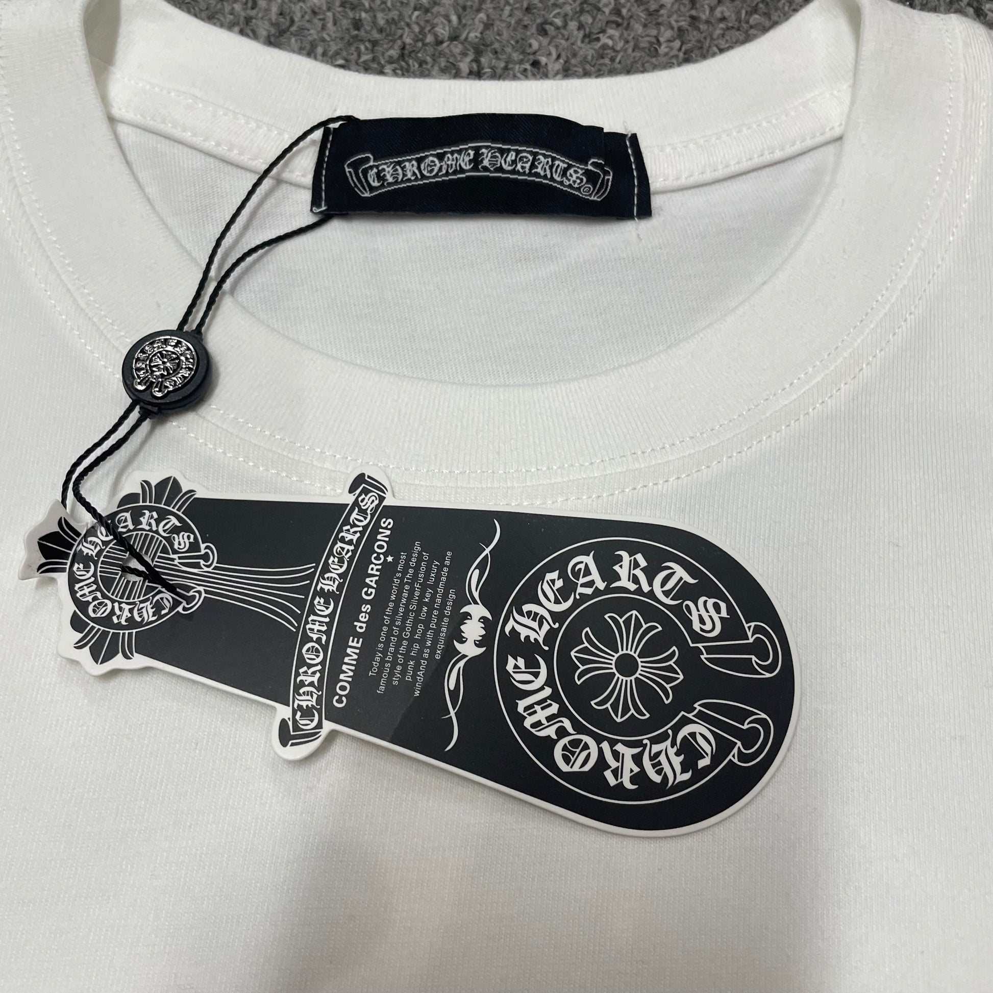 Chrome Hearts Floral Horseshoe T-shirt crew neck stitching hang tag and neck label details
Close-up of the crew neck stitching on Chrome Hearts Floral Horseshoe short sleeve T-shirt
Chrome Hearts Floral Horseshoe T-shirt hang tag and branded neck label close-up
