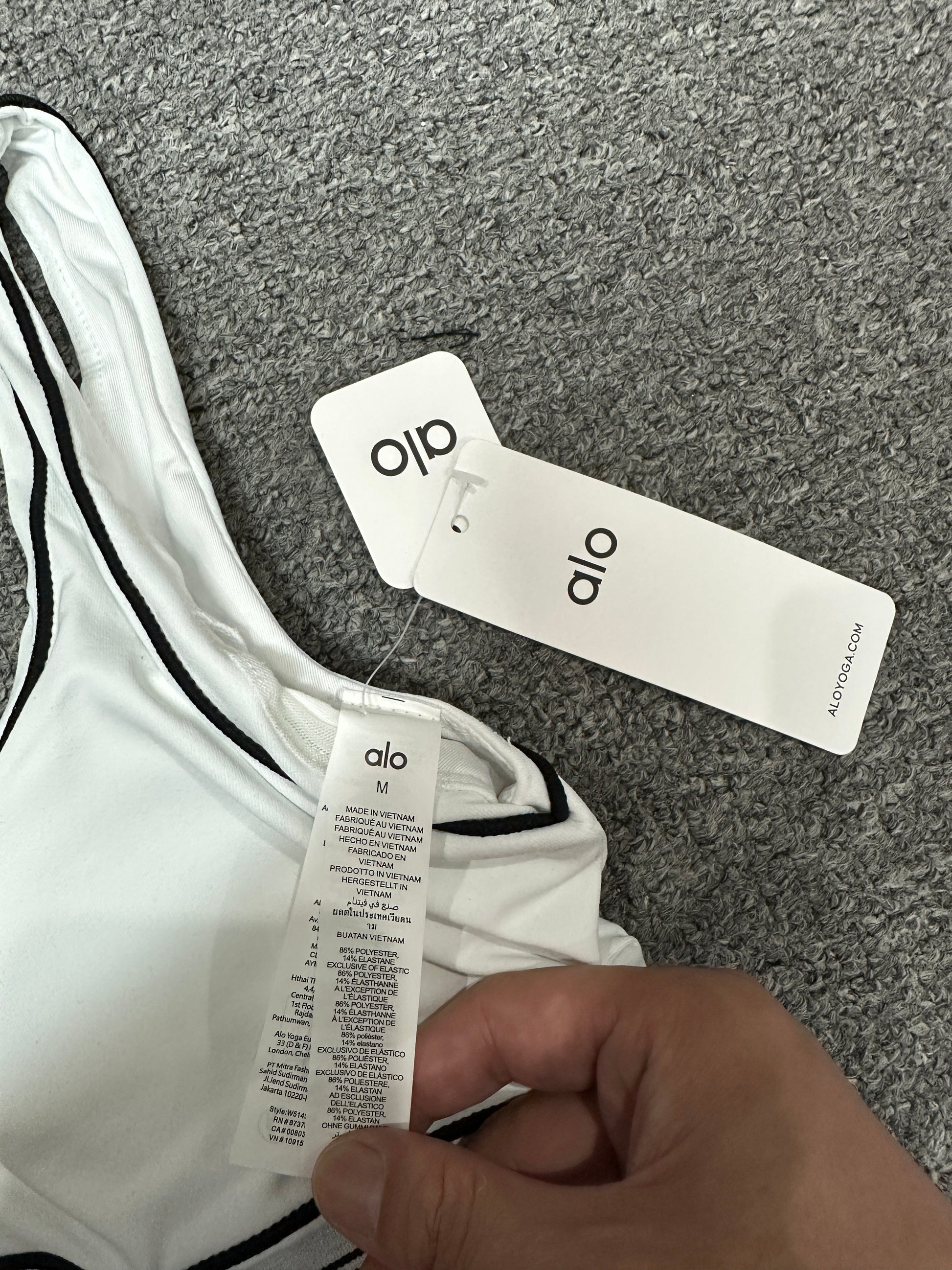 ALO Heart Throb White Black bra scoop neckline and contrast piping detail
ALO Heart Throb White Black sports bra shoulder strap stitching detail
ALO Heart Throb White Black sports bra inner label and size detail
ALO Heart Throb White Black activewear set with branded retail hangtags
ALO Heart Throb White Black workout set care label and fabric information