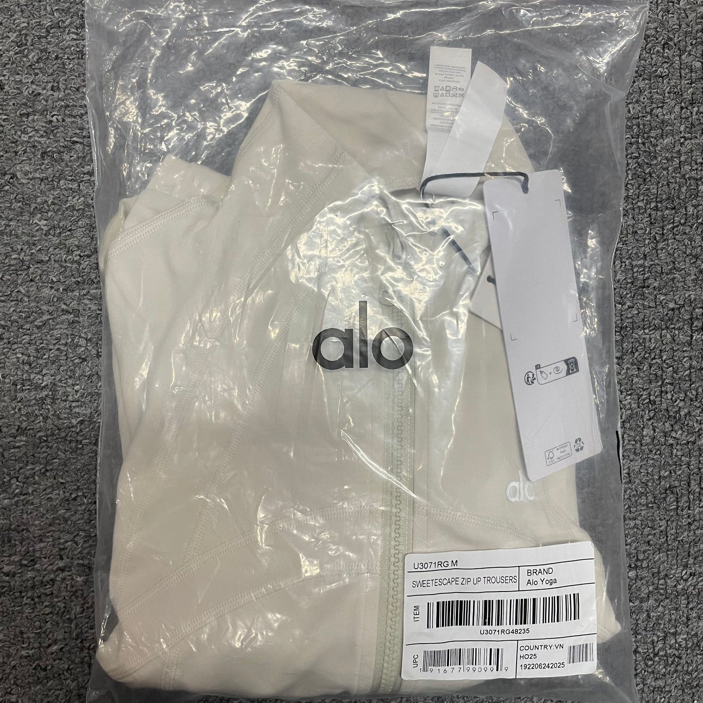 ALO Airbrush Ivory Corset Full Zip Jacket folded inside branded packaging bag