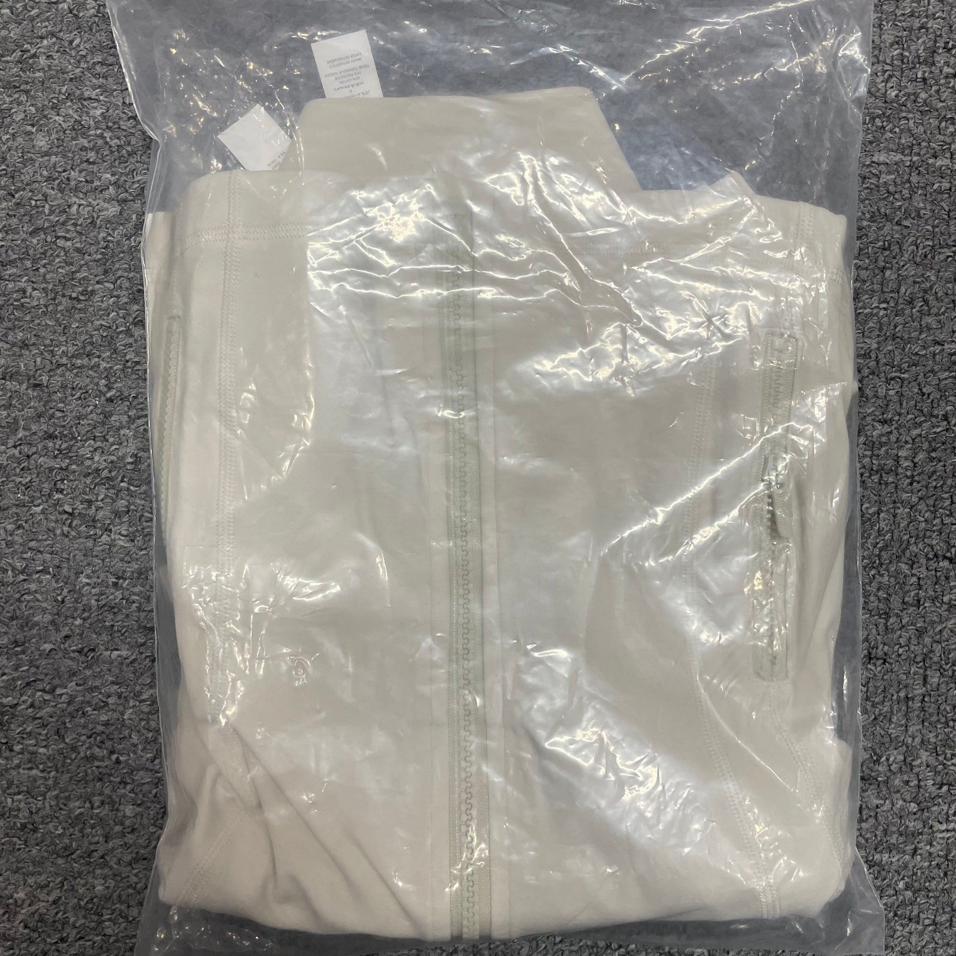ALO Airbrush Ivory Corset Full Zip Jacket folded inside branded packaging bag