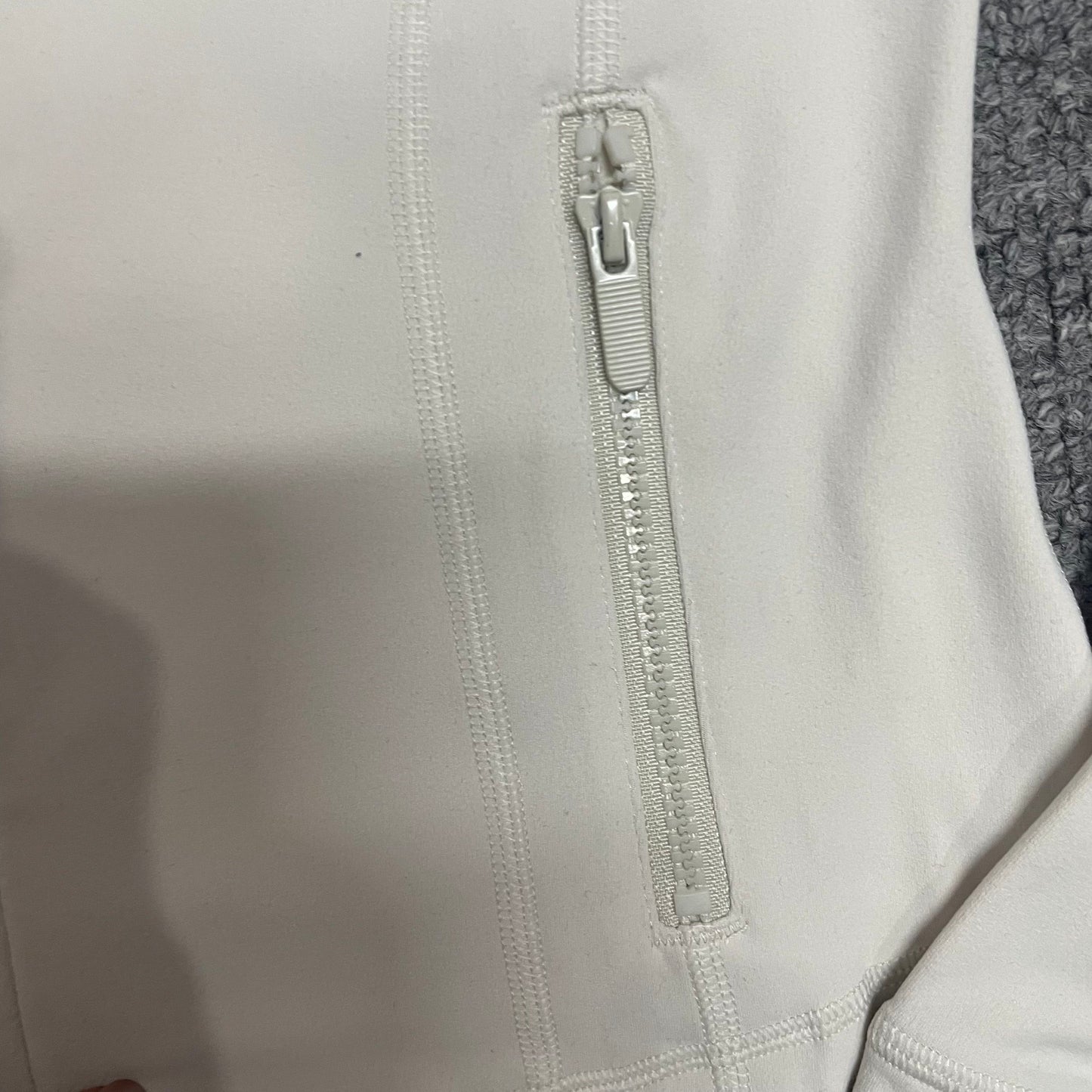 Curved corset seam construction on Ivory ALO Airbrush Full Zip Jacket
ALO Airbrush Ivory jacket full front zipper and zipper pull detail
Zippered hip pocket detail on Ivory ALO Airbrush Corset Jacket