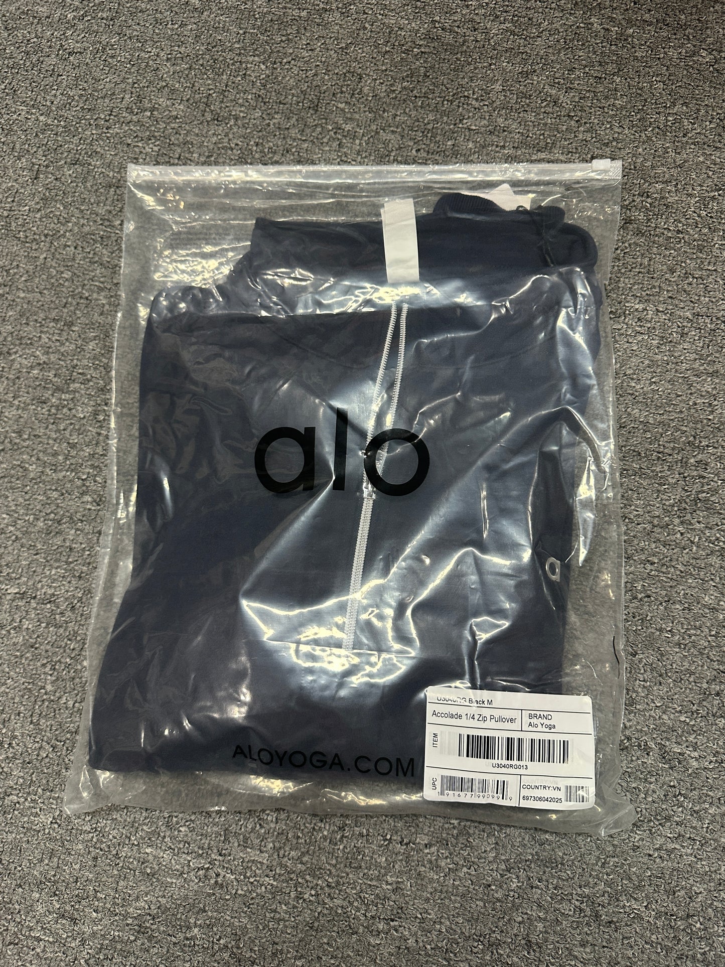 ALO Accolade Navy quarter zip pullover folded inside branded zip packaging bag