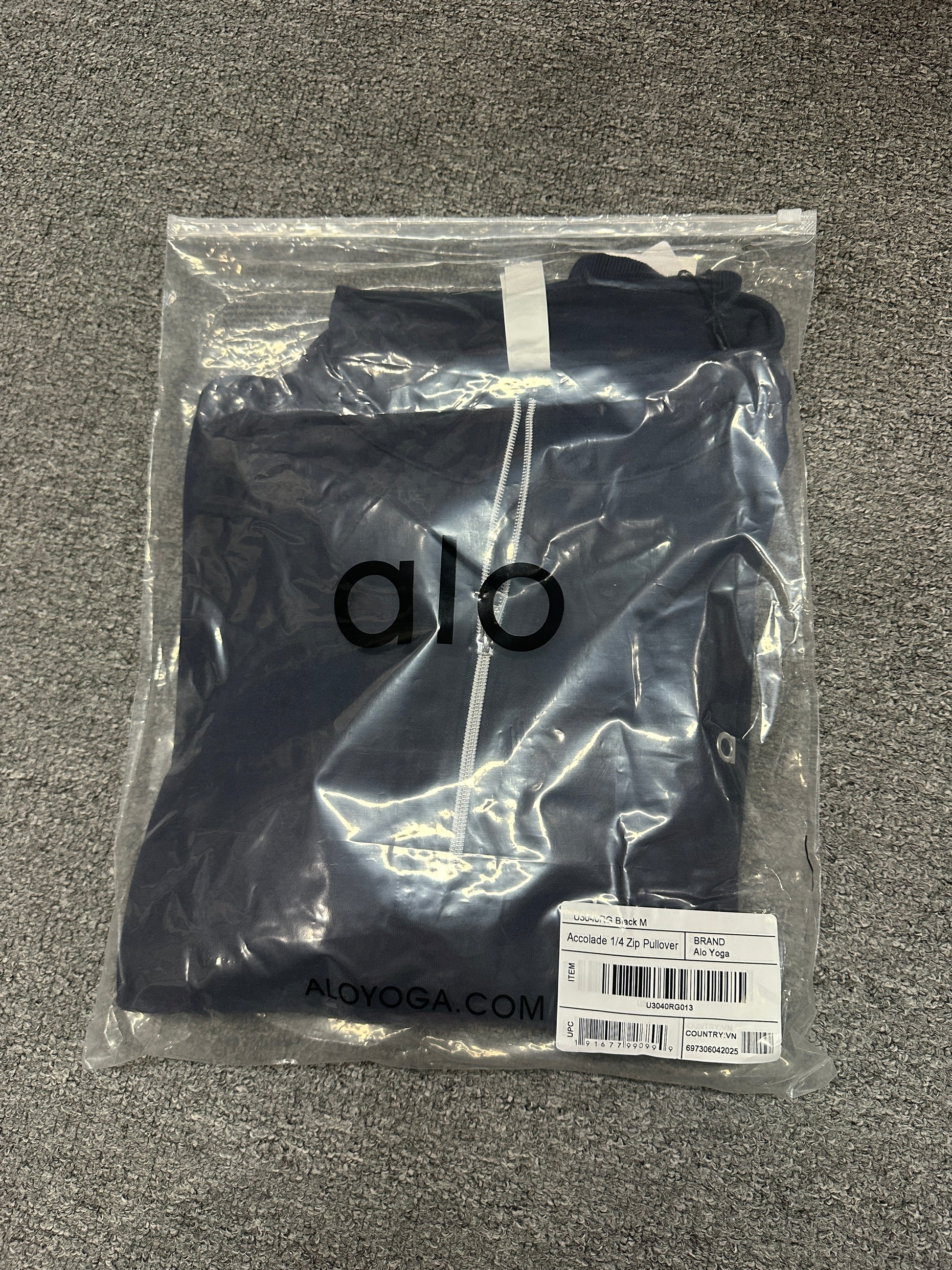 ALO Accolade Navy quarter zip pullover folded inside branded zip packaging bag