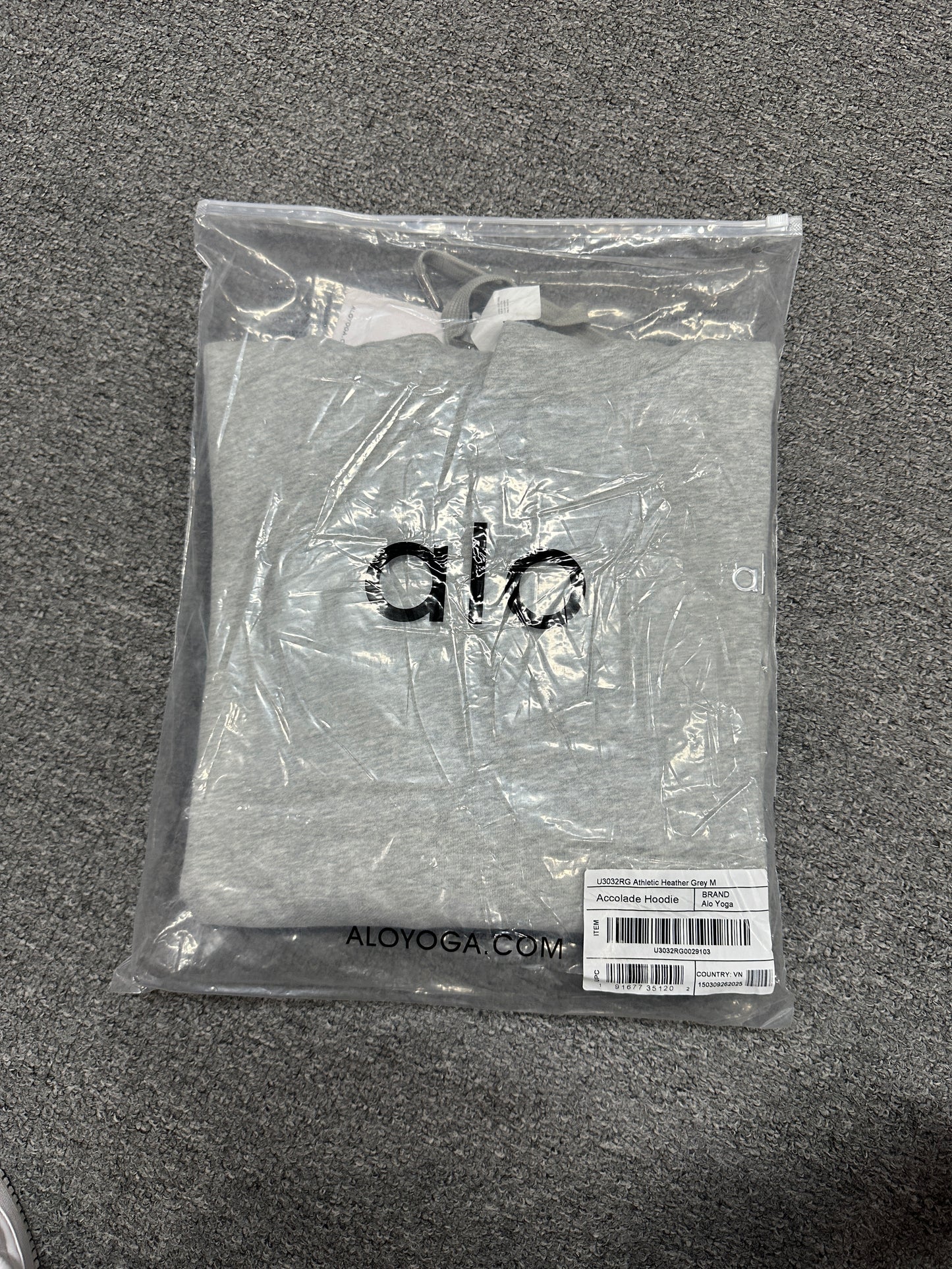 ALO Accolade Athletic Heather Grey hoodie folded inside branded zip packaging bag
