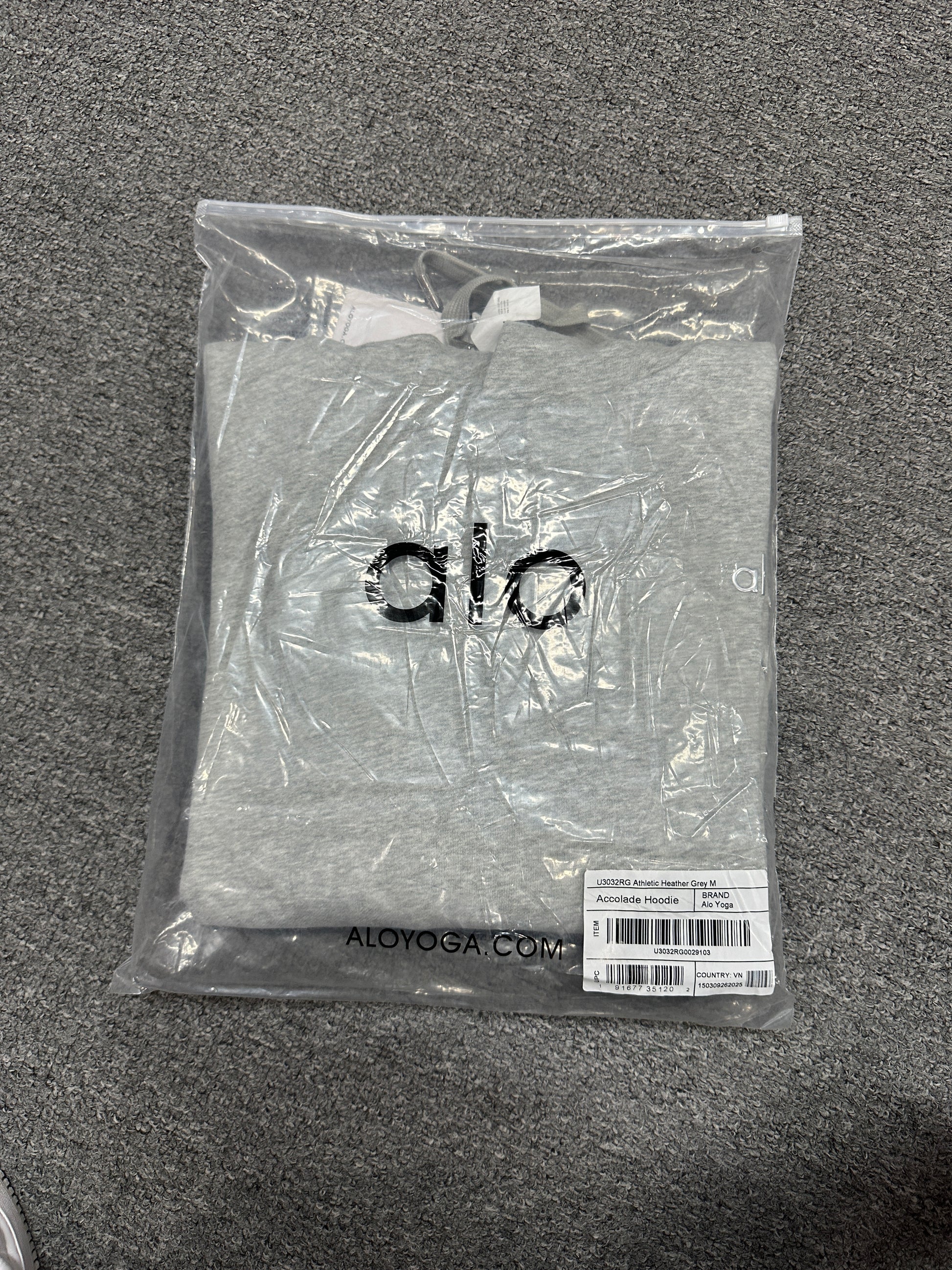 ALO Accolade Athletic Heather Grey hoodie folded inside branded zip packaging bag