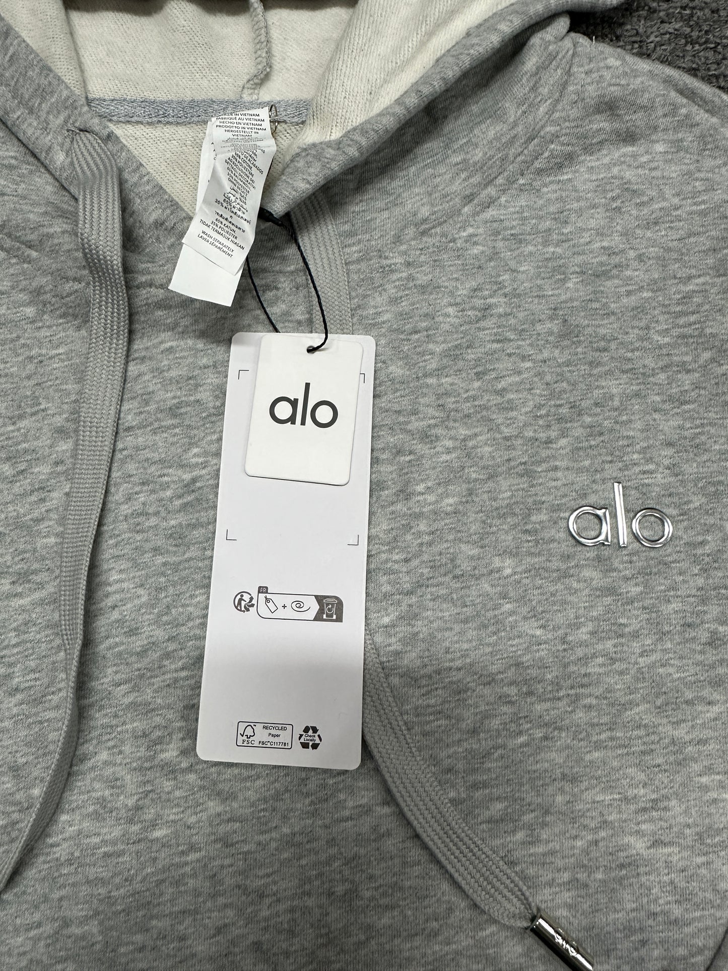 ALO Accolade Athletic Heather Grey hood, neckline and drawstring construction detail
ALO Accolade Athletic Heather Grey hoodie neck label and size label close-up
ALO Accolade Athletic Heather Grey hoodie with branded retail hangtags
ALO Accolade Athletic Heather Grey hoodie care label and fabric information detail