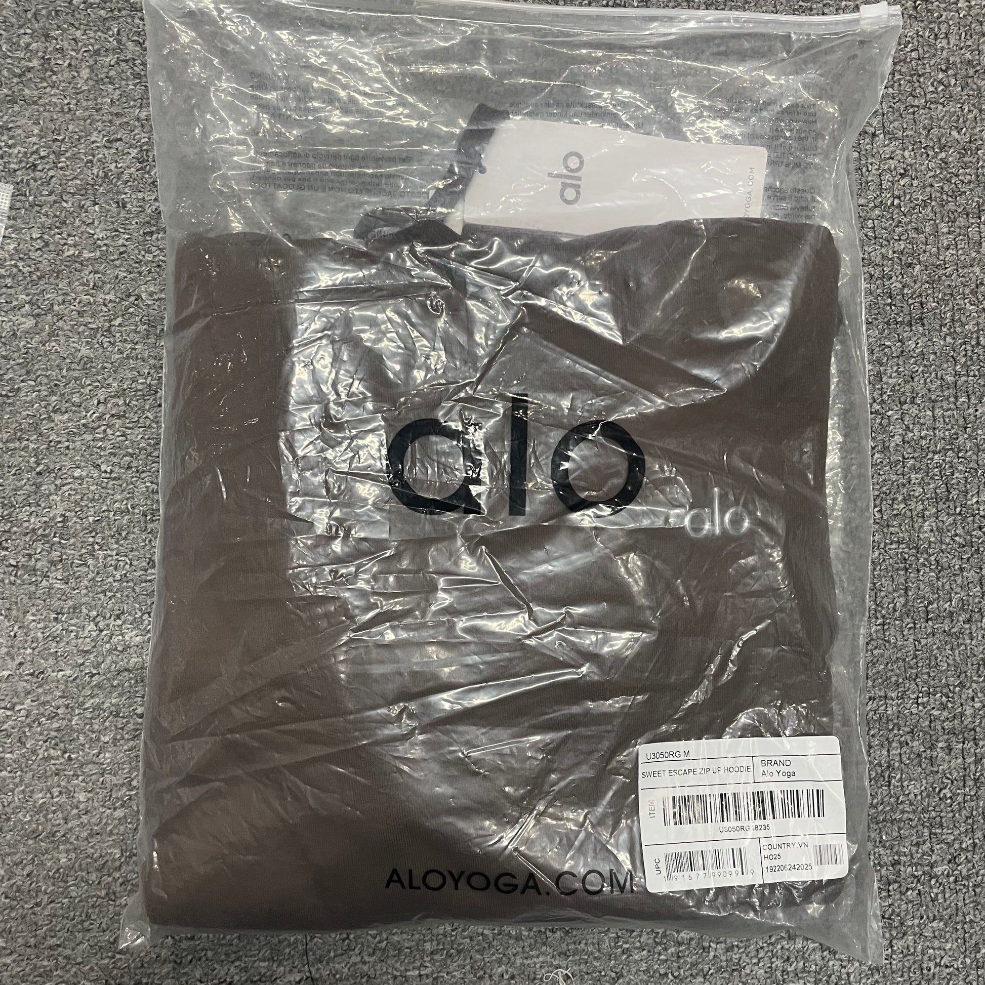 ALO Accolade Espresso hoodie folded inside branded zip packaging bag