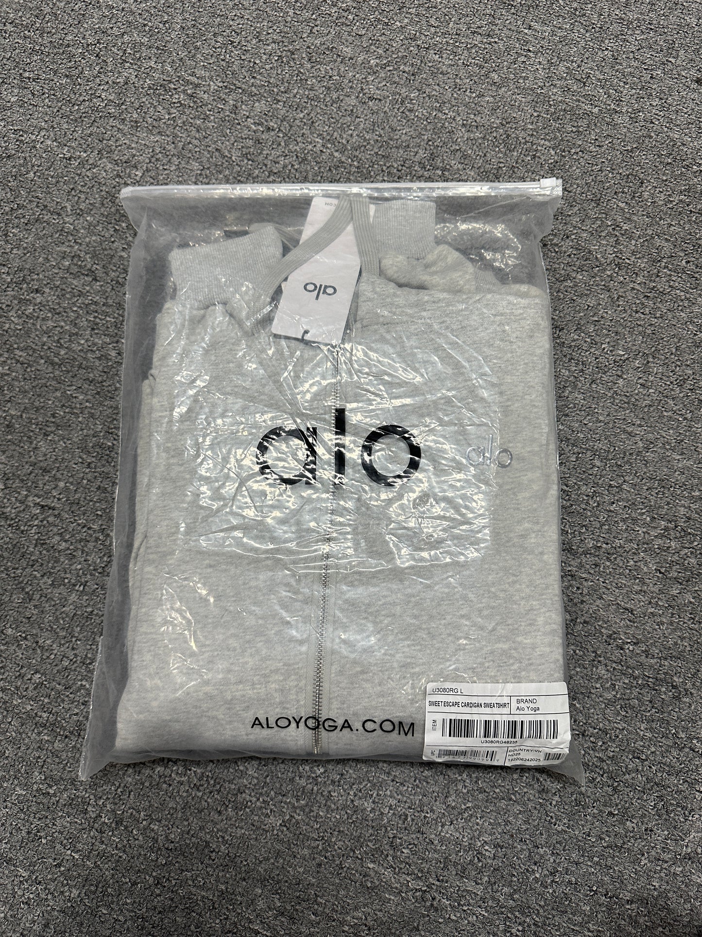 ALO Accolade Athletic Heather Grey hoodie folded inside branded zip packaging bag