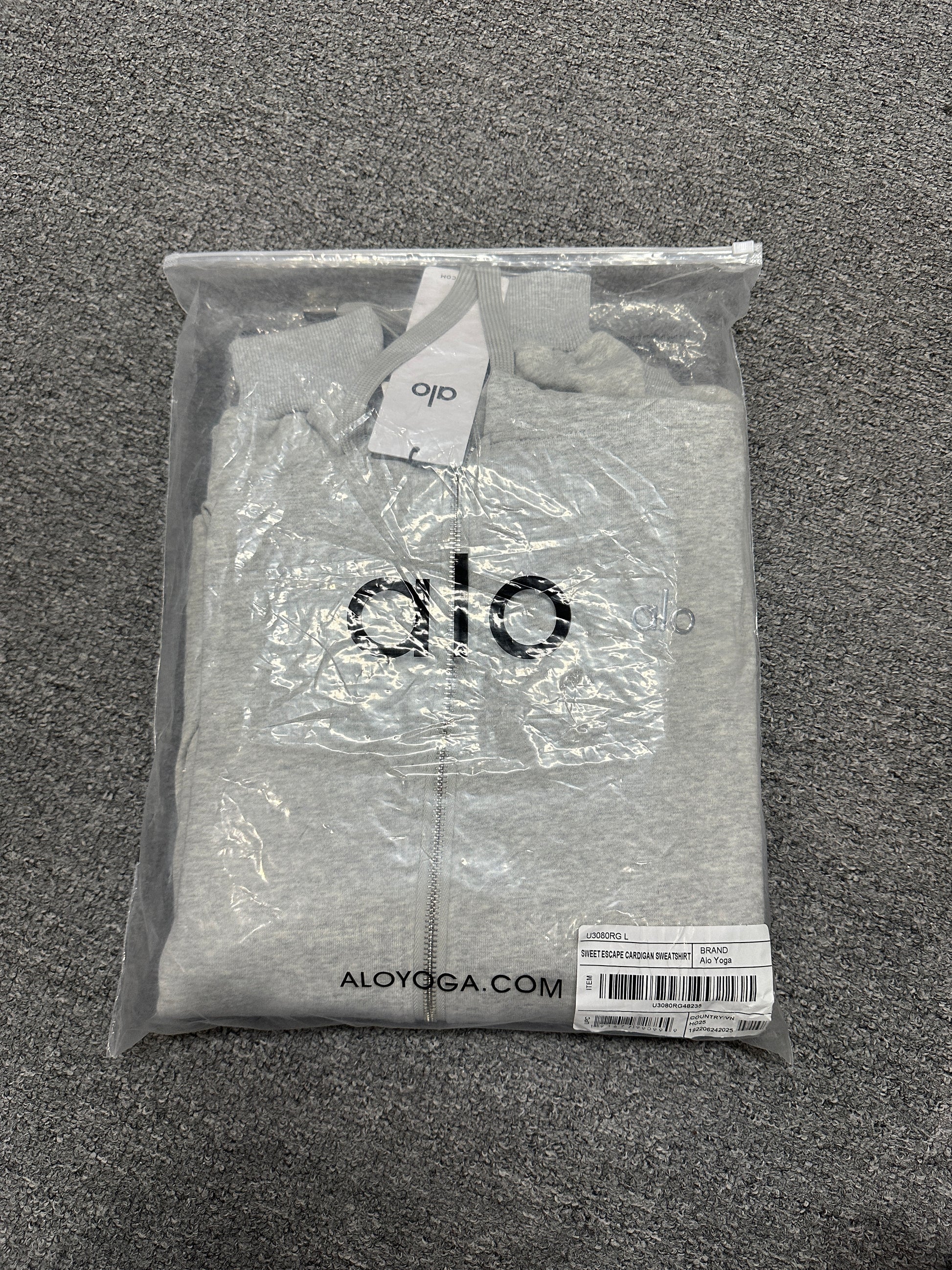 ALO Accolade Athletic Heather Grey hoodie folded inside branded zip packaging bag