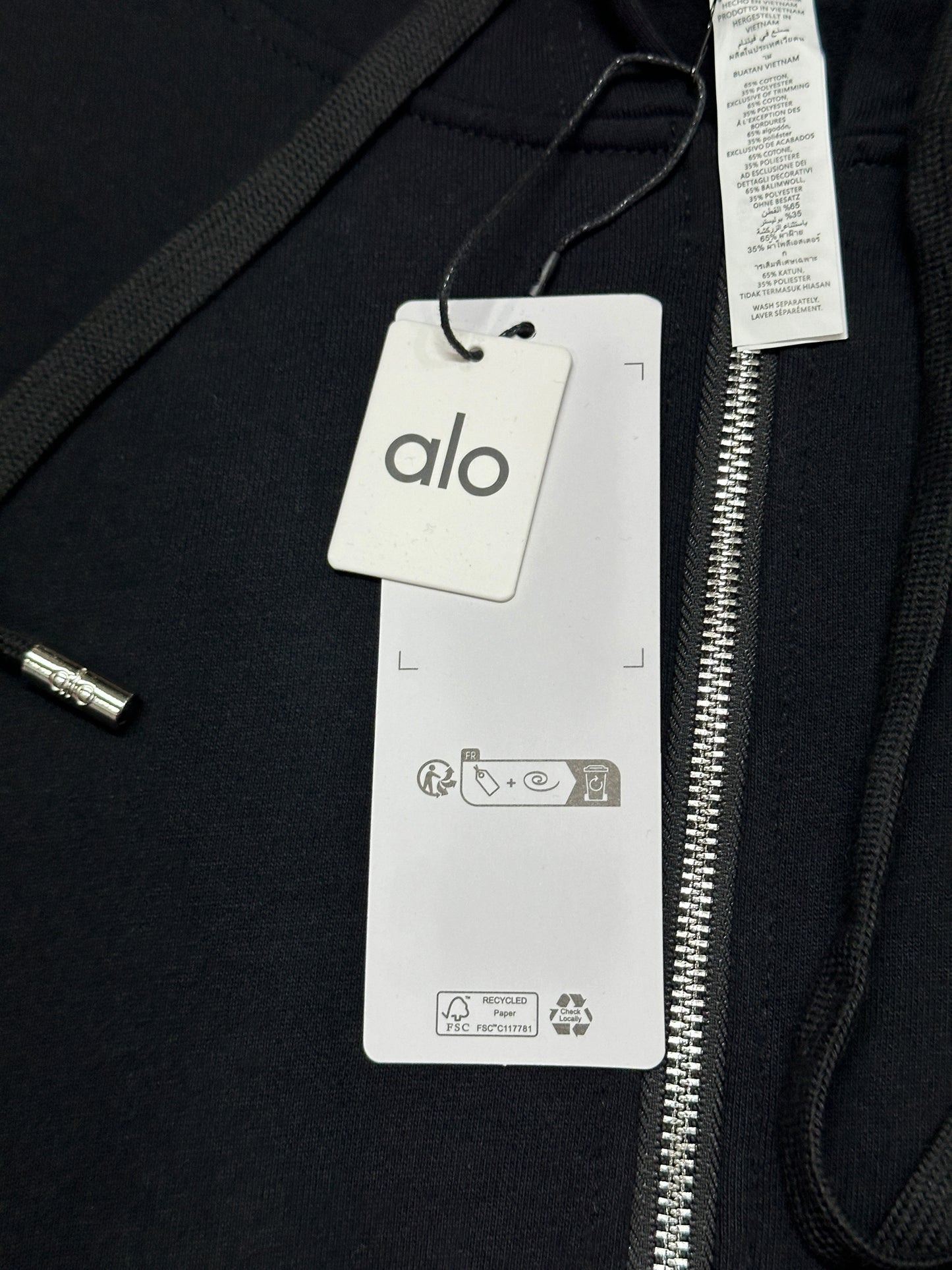 ALO Accolade Black full zip hoodie neckline, hood and drawstring construction detail
ALO Accolade Black full zip hoodie neck label close-up
ALO Accolade Black full zip hoodie size label detail
ALO Accolade Black full zip hoodie with branded retail hangtags