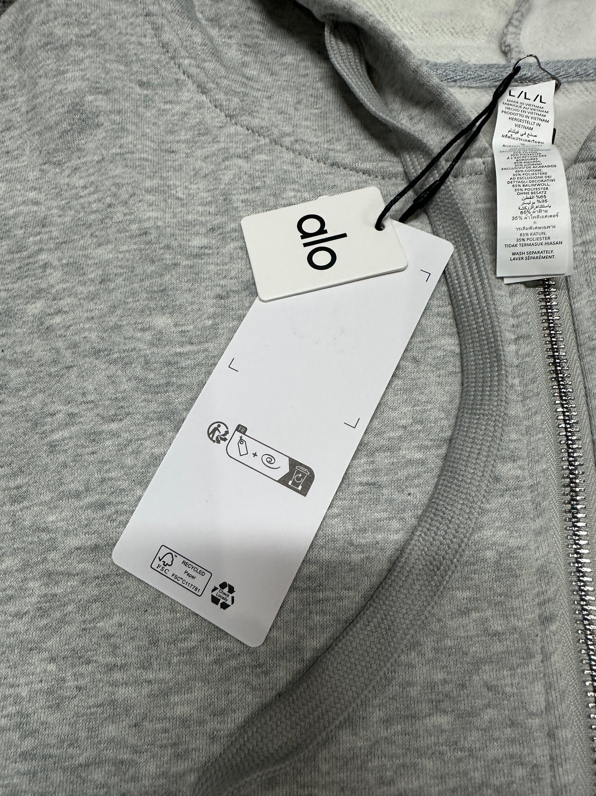 ALO Accolade Athletic Heather Grey hood, neckline and drawstring construction detail
ALO Accolade Athletic Heather Grey full zip hoodie neck label close-up
ALO Accolade Athletic Heather Grey full zip hoodie size label detail
ALO Accolade Athletic Heather Grey full zip hoodie with branded retail hangtags