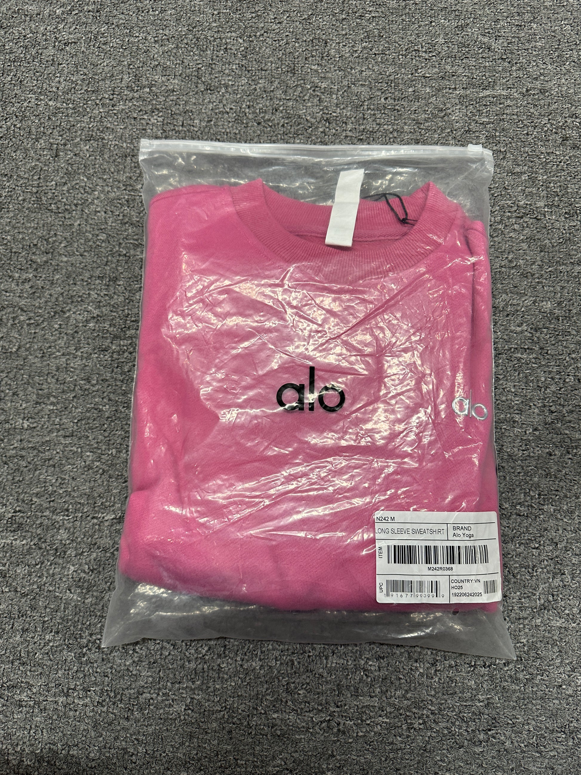 ALO Accolade Paradise Pink crewneck folded inside branded zip packaging bag