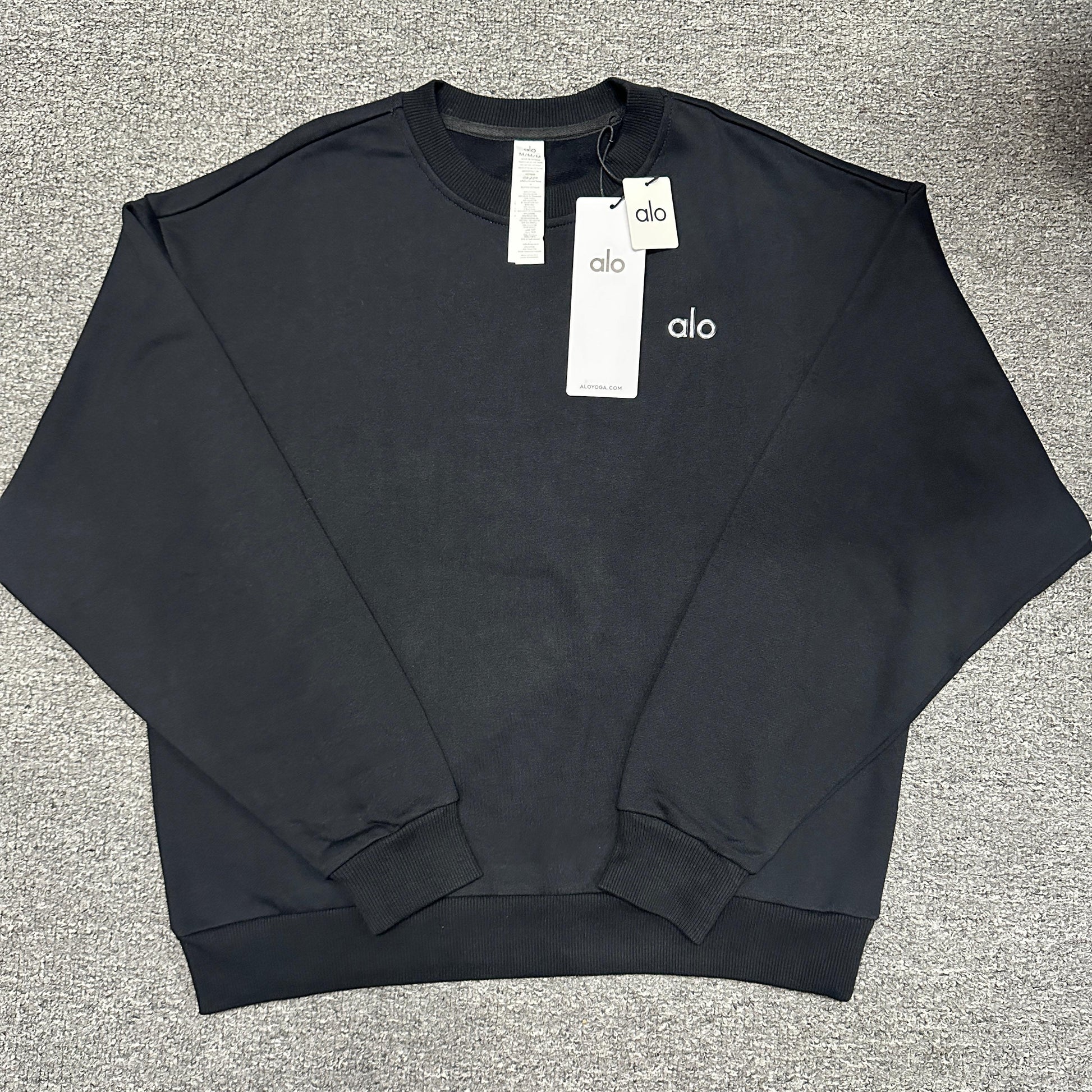 ALO Accolade Crew Neck Pullover in Black front view with silver chest logo