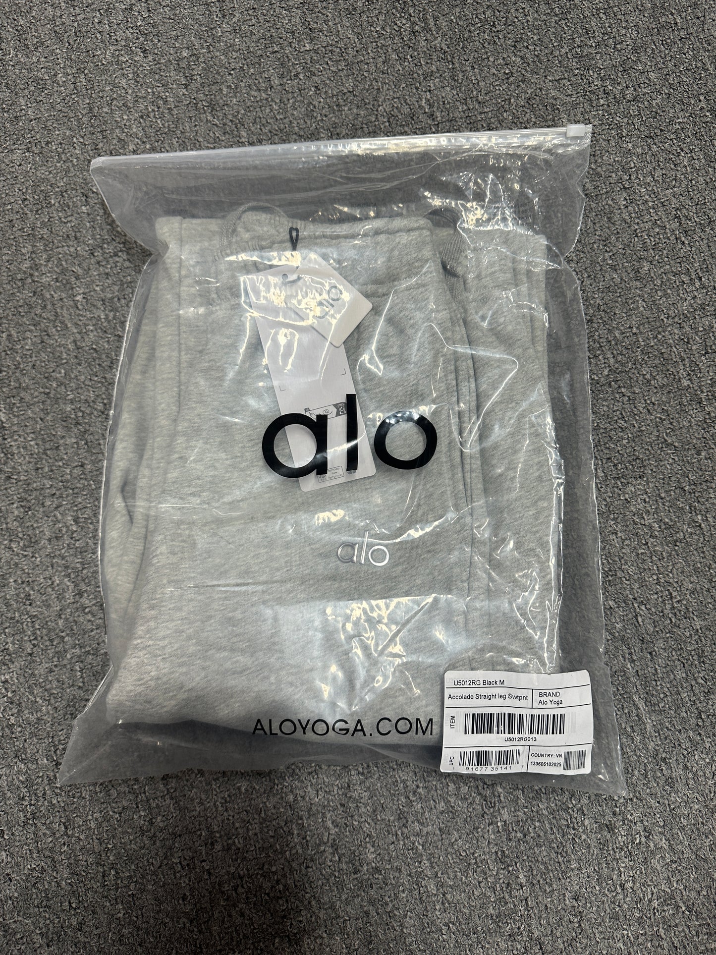 ALO Accolade Athletic Heather Grey straight leg sweatpant folded inside branded zip packaging bag