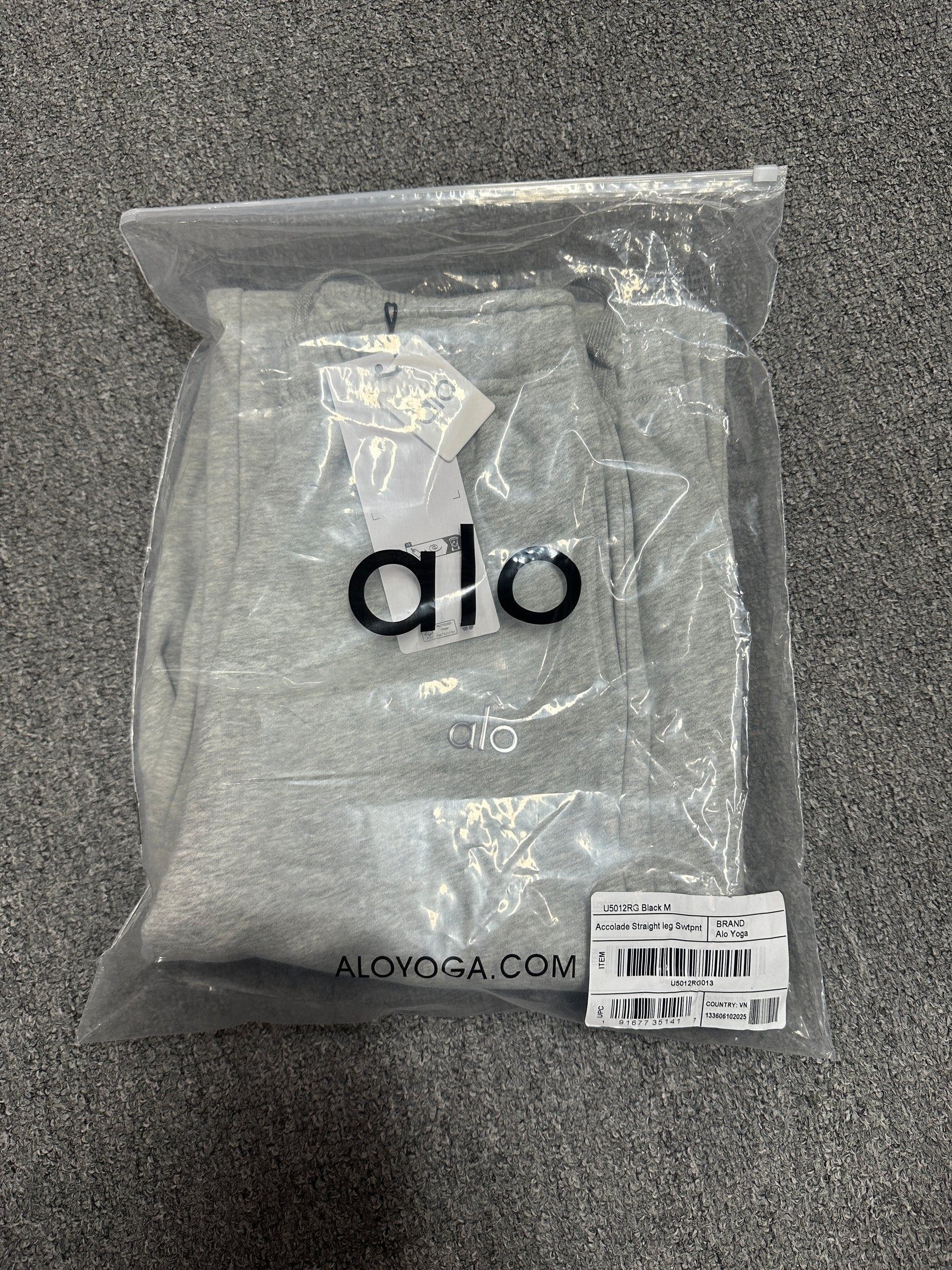 ALO Accolade Athletic Heather Grey straight leg sweatpant folded inside branded zip packaging bag