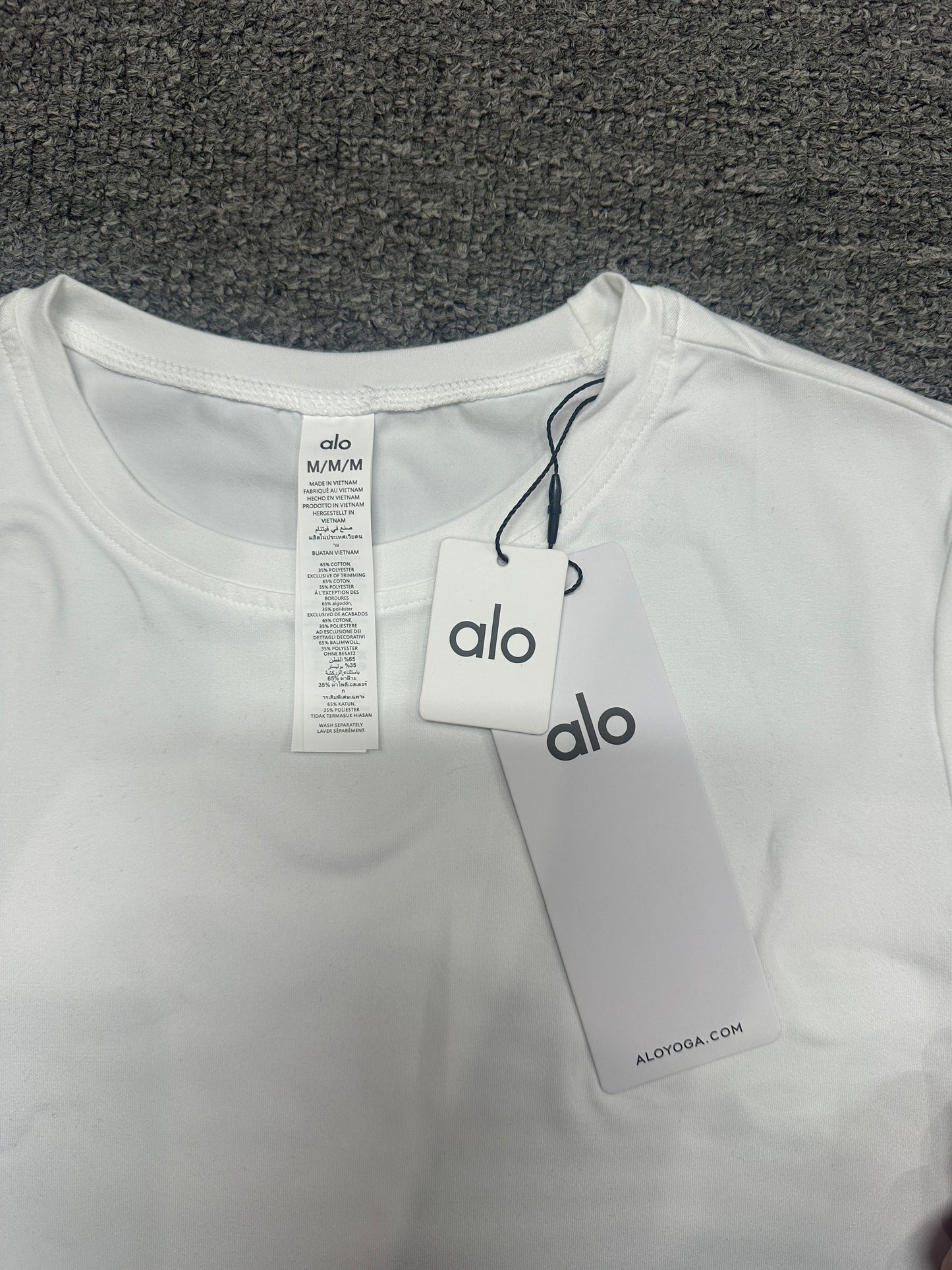 ALO Alosoft White crop tee neck label and size label close-up
ALO Alosoft White Crop Finesse Short Sleeve with branded retail hangtags