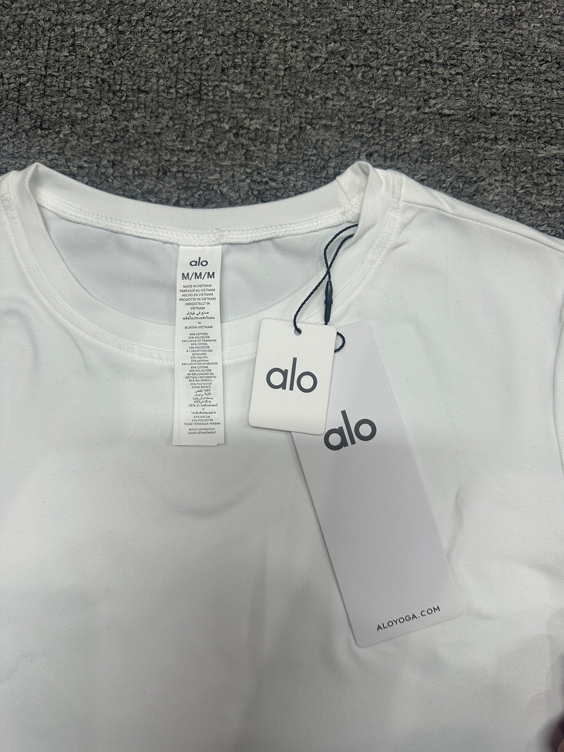 ALO Alosoft White crop tee neck label and size label close-up
ALO Alosoft White Crop Finesse Short Sleeve with branded retail hangtags