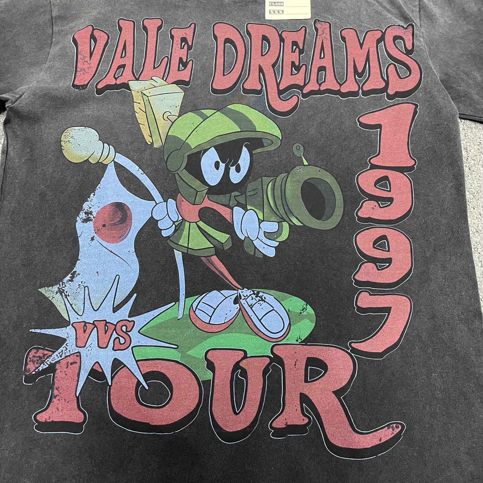 Vale Forever Marvins Dreams Tee full 1997 Tour front graphic
Vale Forever Marvins Dreams Tee Martian character and 1997 Tour artwork
Vale Forever Marvins Dreams Tee distressed vintage graphic close-up
Vale Forever Marvins Dreams Tee distressed red Vale Dreams lettering
Vale Forever Marvins Dreams Tee green Martian character graphic detail
Vale Forever Marvins Dreams Tee Martian helmet and face print close-up
Vale Forever Marvins Dreams Tee cartoVale Forever Marvins Dreams Teeon space blaster graphic detail
