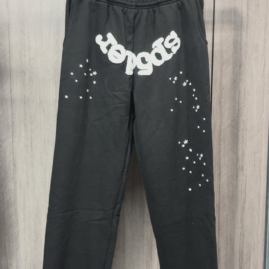 SP5DER OG Web black sweatpants front view with white logo and scattered star graphics
