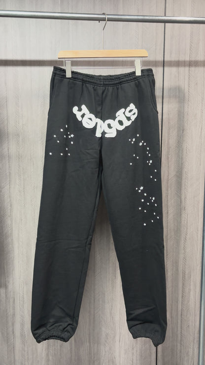 SP5DER OG Web black sweatpants front view with white logo and scattered star graphics