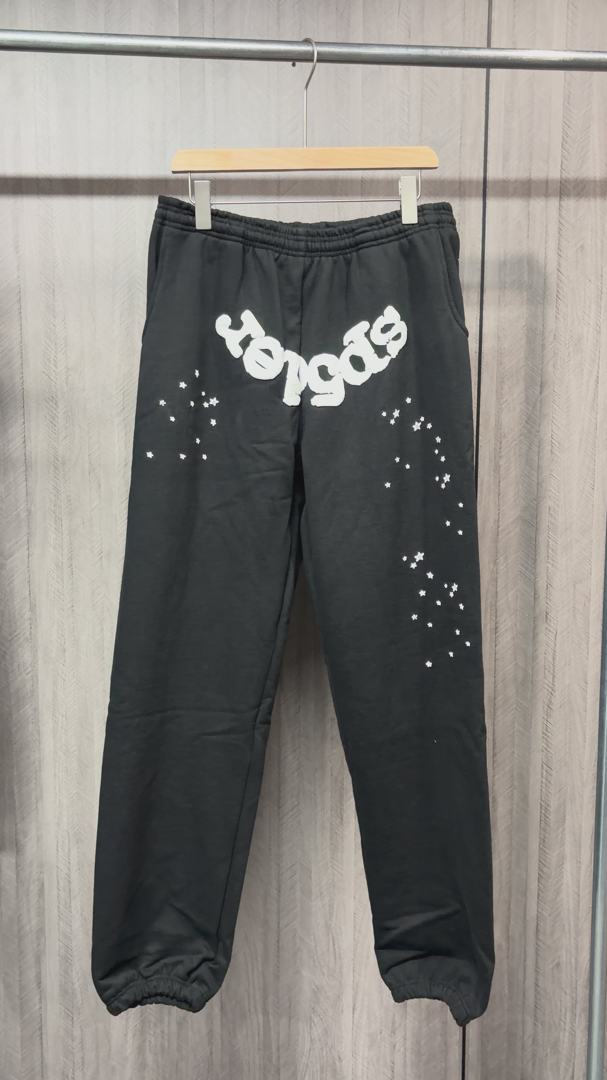 SP5DER OG Web black sweatpants front view with white logo and scattered star graphics