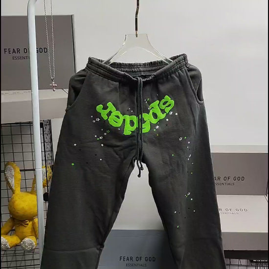 SP5DER Wait Web slate grey sweatpants front view with neon green logo and scattered stars